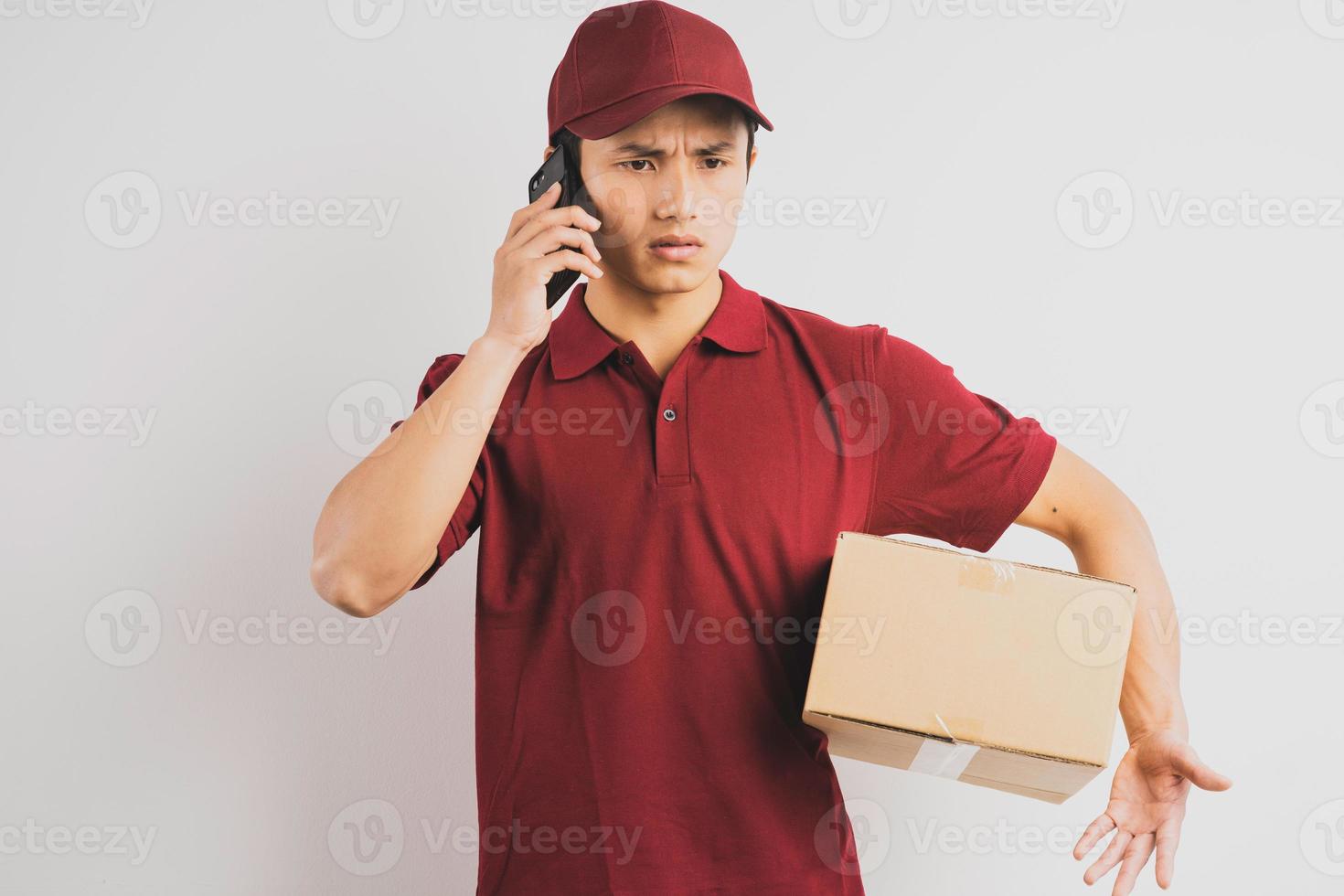 Retrato de un repartidor sosteniendo una caja de carga y escuchando el teléfono en el fondo foto