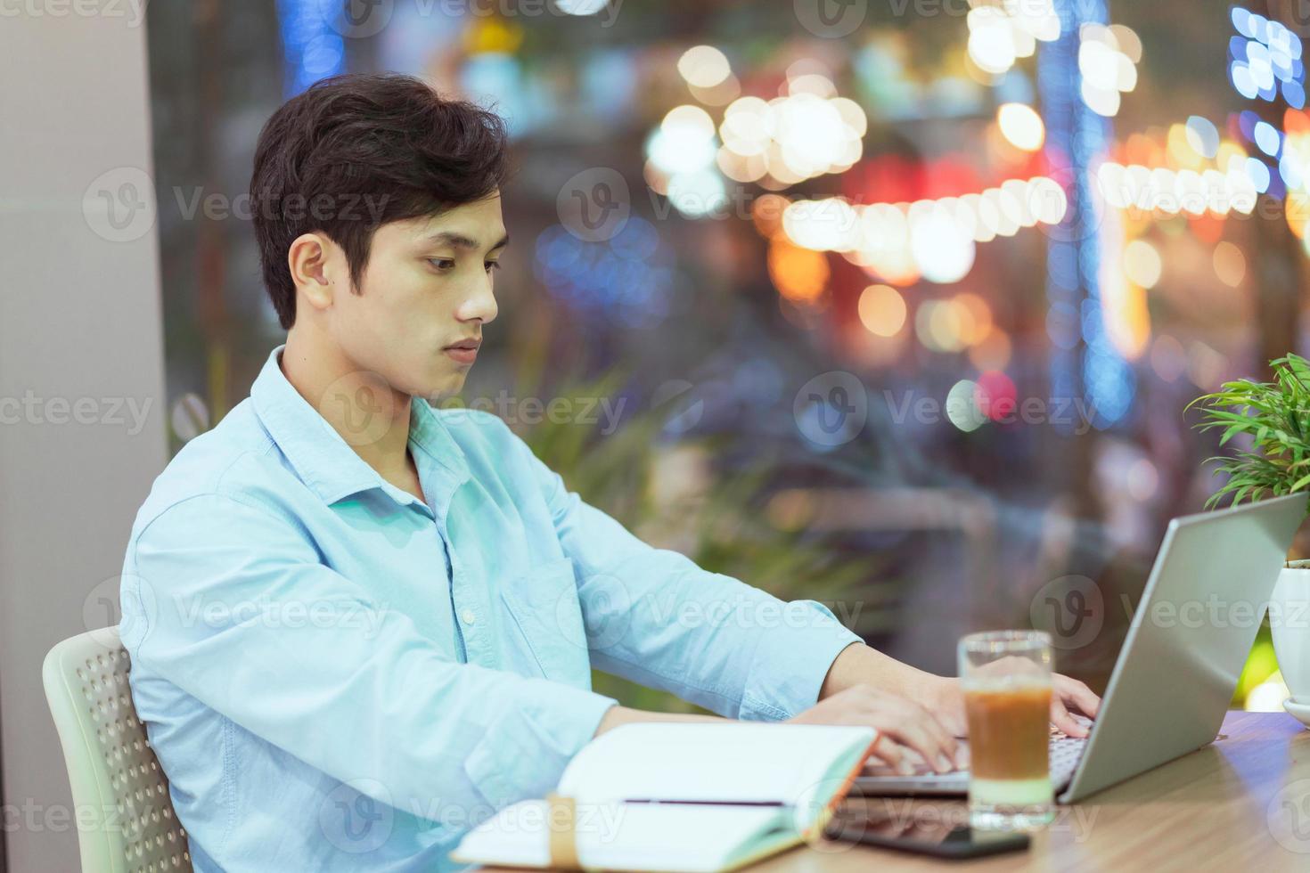 Hombre asiático sentado trabajando solo en una cafetería. foto