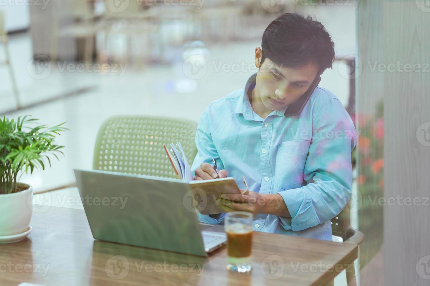 Asian man sitting working alone at a coffee shop photo