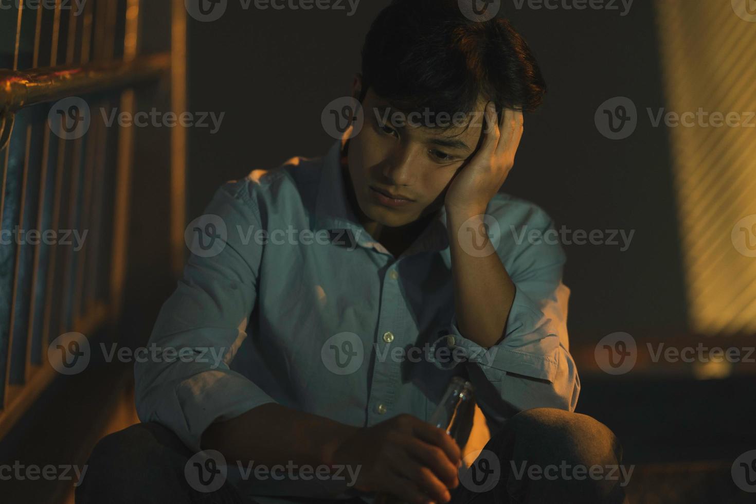 The tired Asian man is drinking alone on the outdoor staircase photo