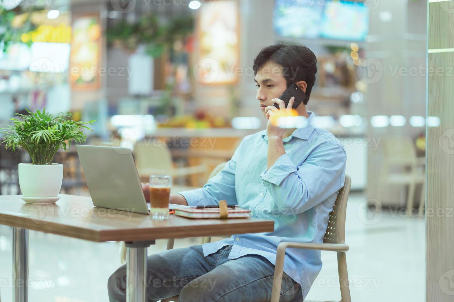 Asian man sitting working alone at a coffee shop photo