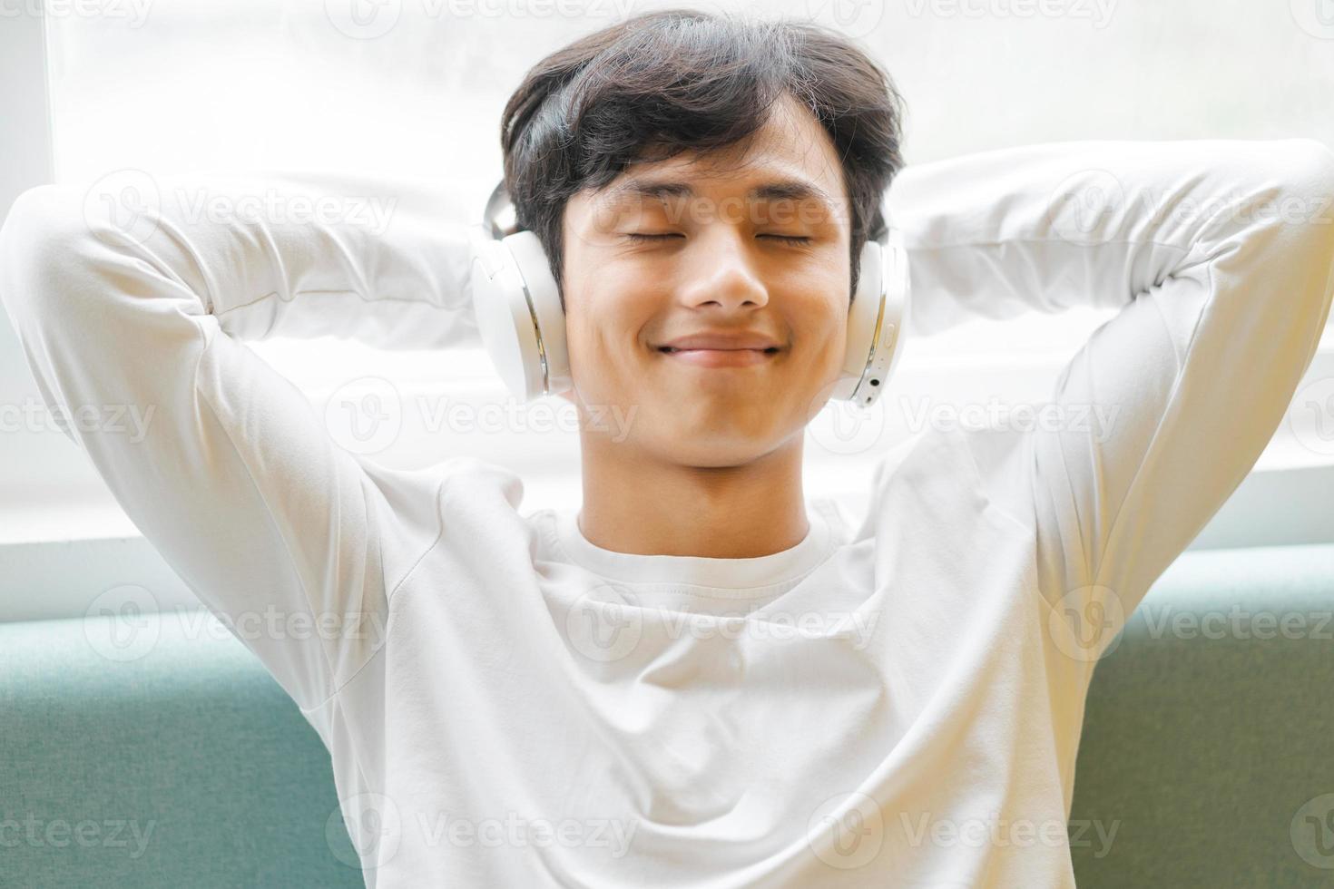 Asian man sitting, enjoying music photo