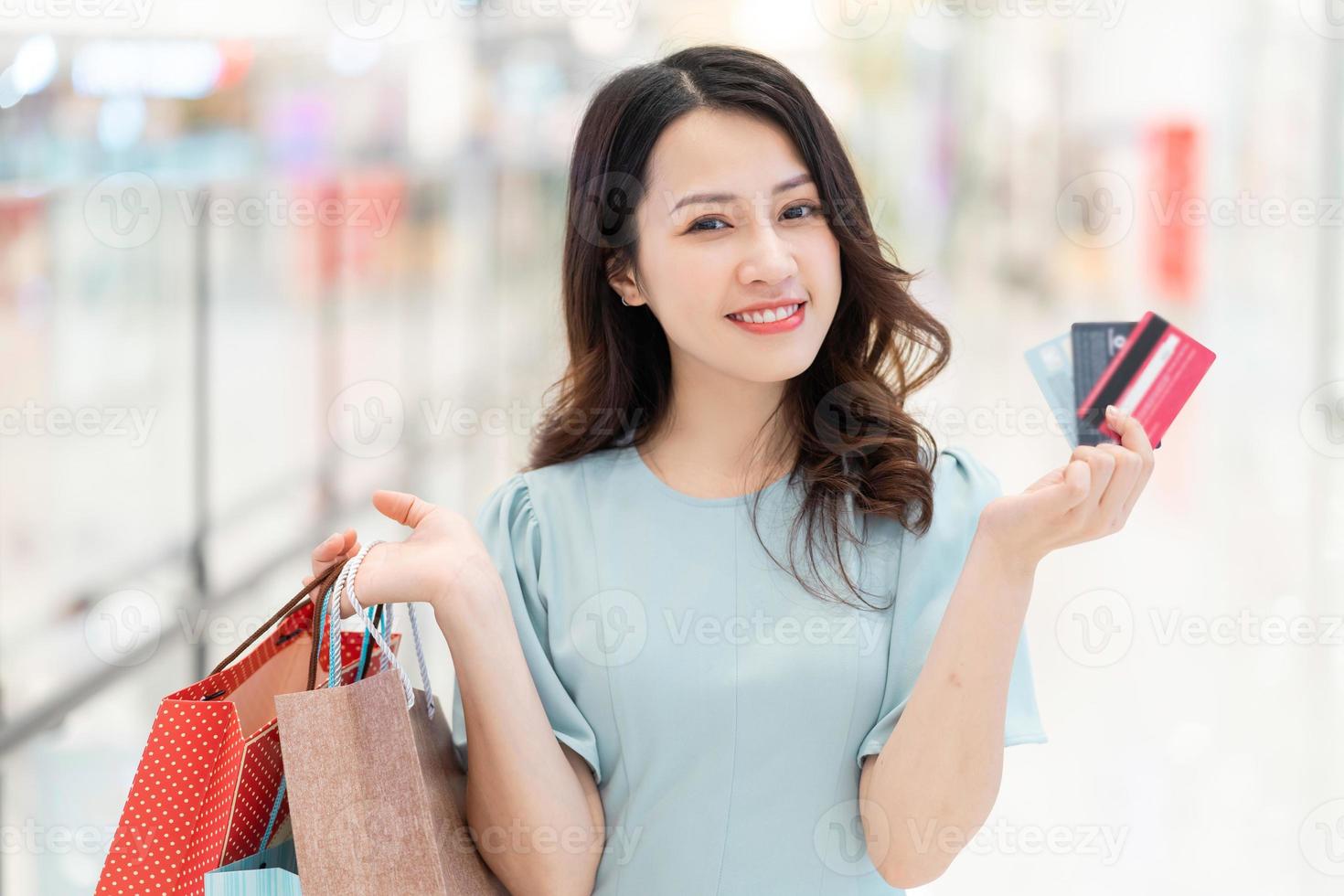 niña de pie sosteniendo una tarjeta de crédito en el centro comercial foto