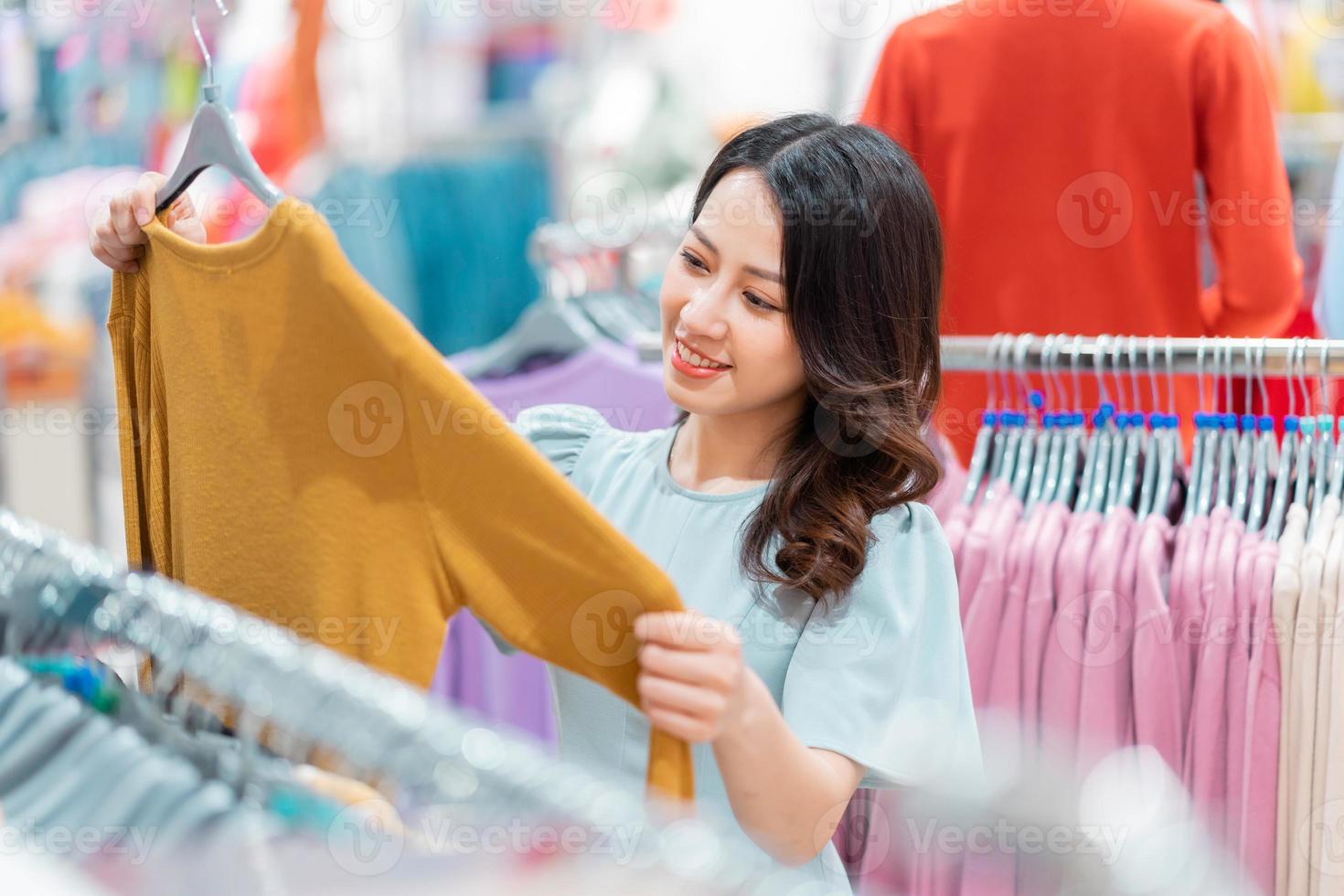 Young girl is choosing to buy clothes at the mall photo