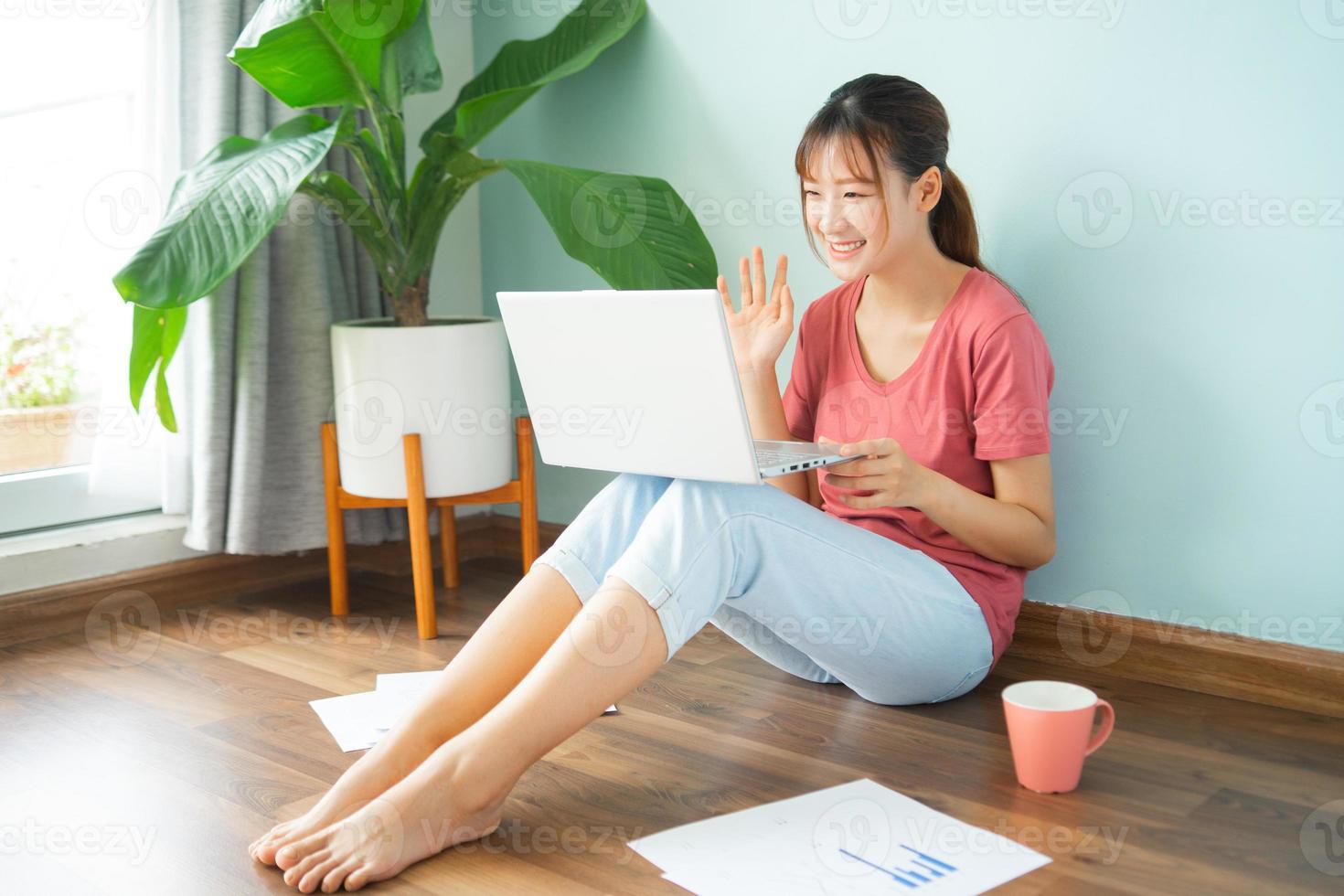 Asian woman sitting on the floor while she working from home photo