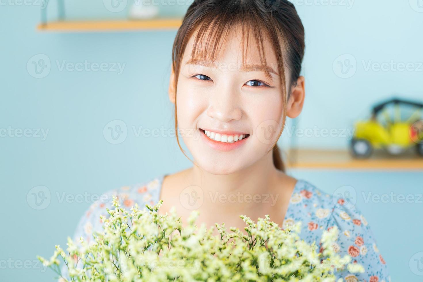 una joven mujer asiática sosteniendo flores en su habitación foto