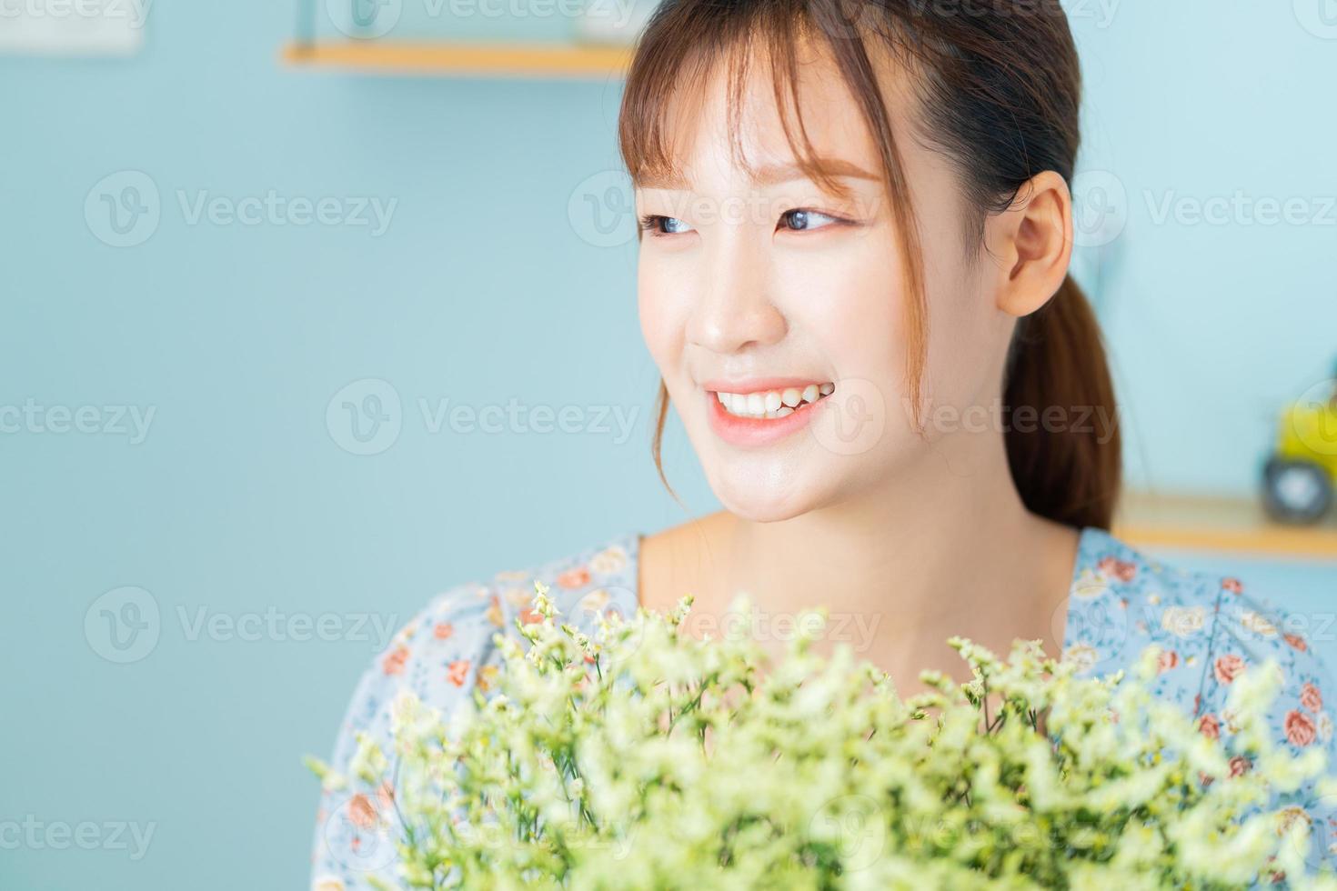 una joven mujer asiática sosteniendo flores en su habitación foto