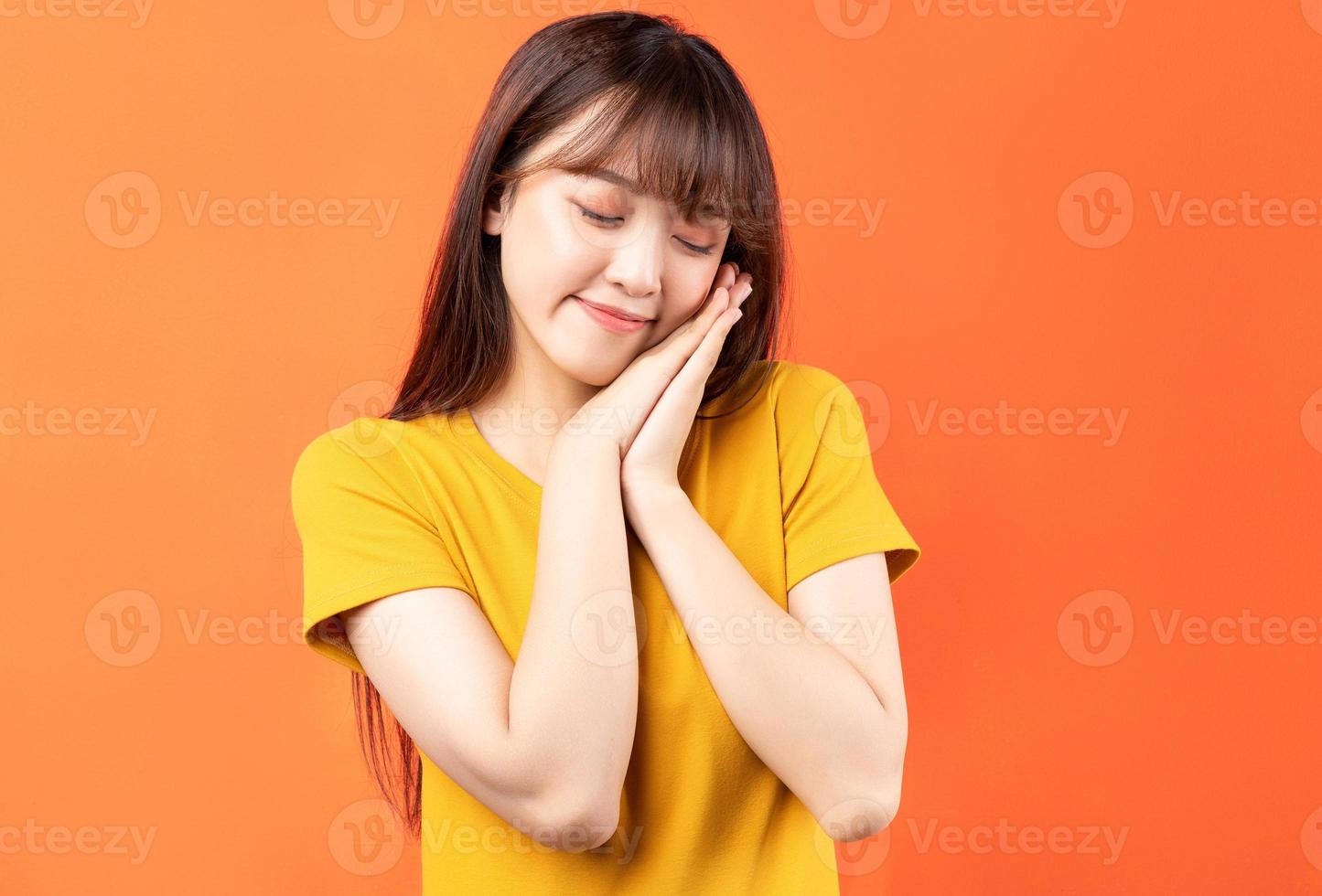 Image of young Asian woman wearing yellow t-shirt on orange background photo