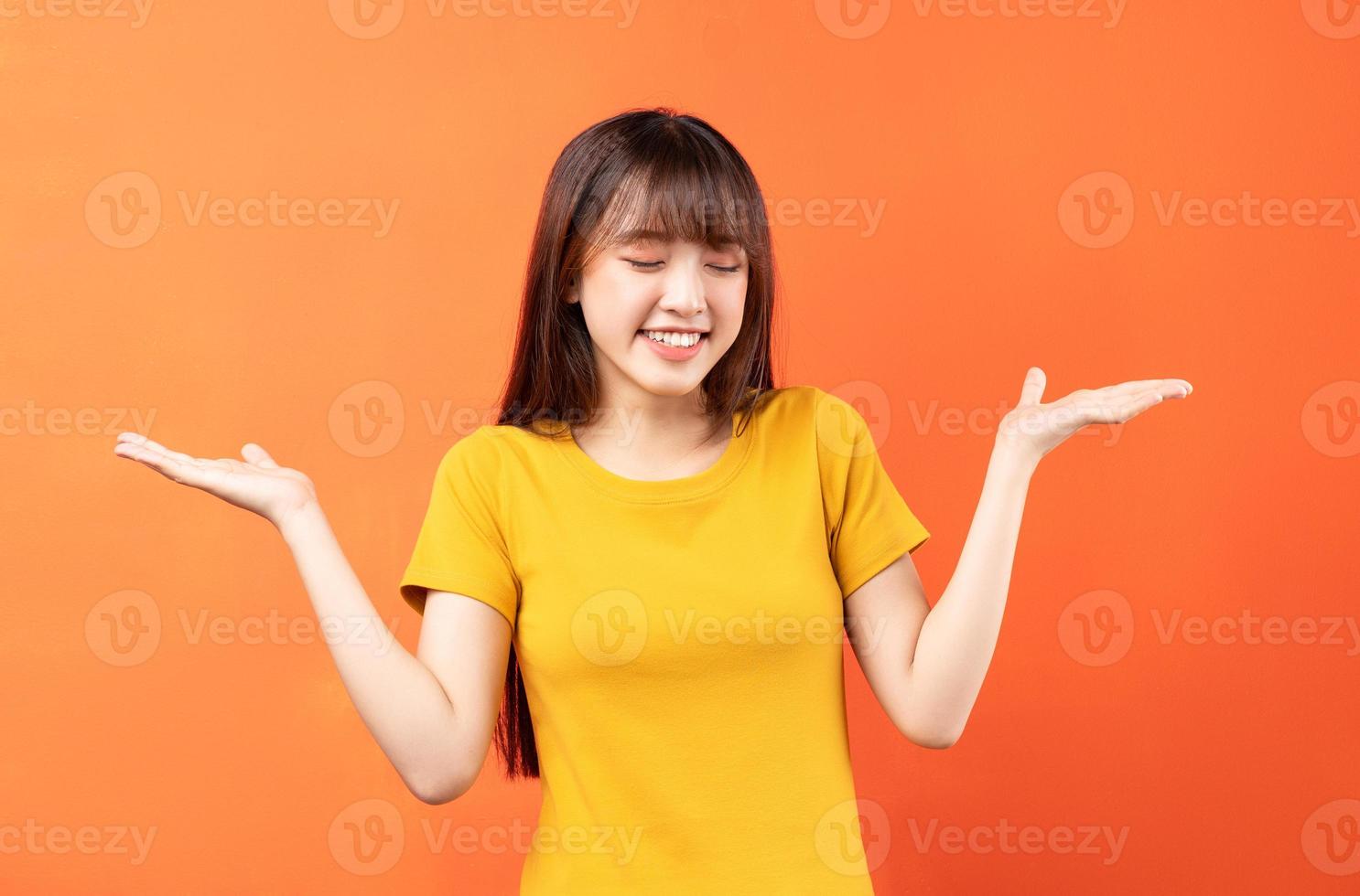 Imagen de una joven asiática con camiseta amarilla sobre fondo naranja foto