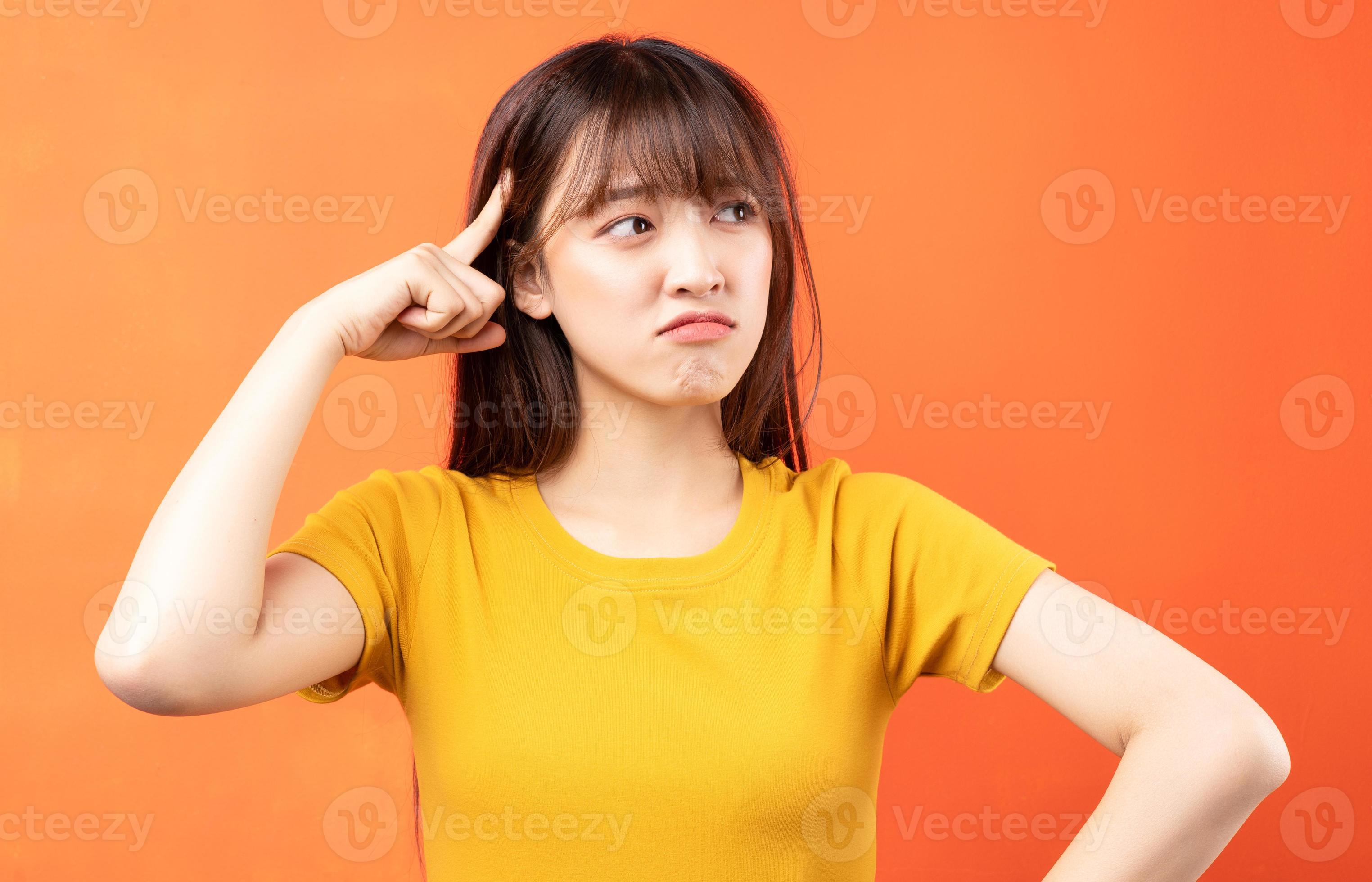 Image of young Asian woman wearing yellow t-shirt on orange background photo