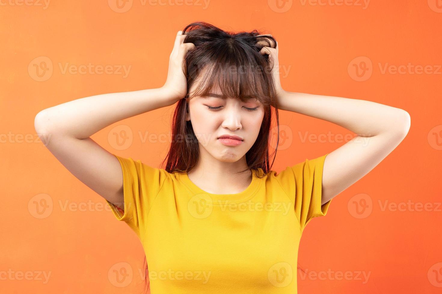 Image of young Asian woman wearing yellow t-shirt on orange background photo