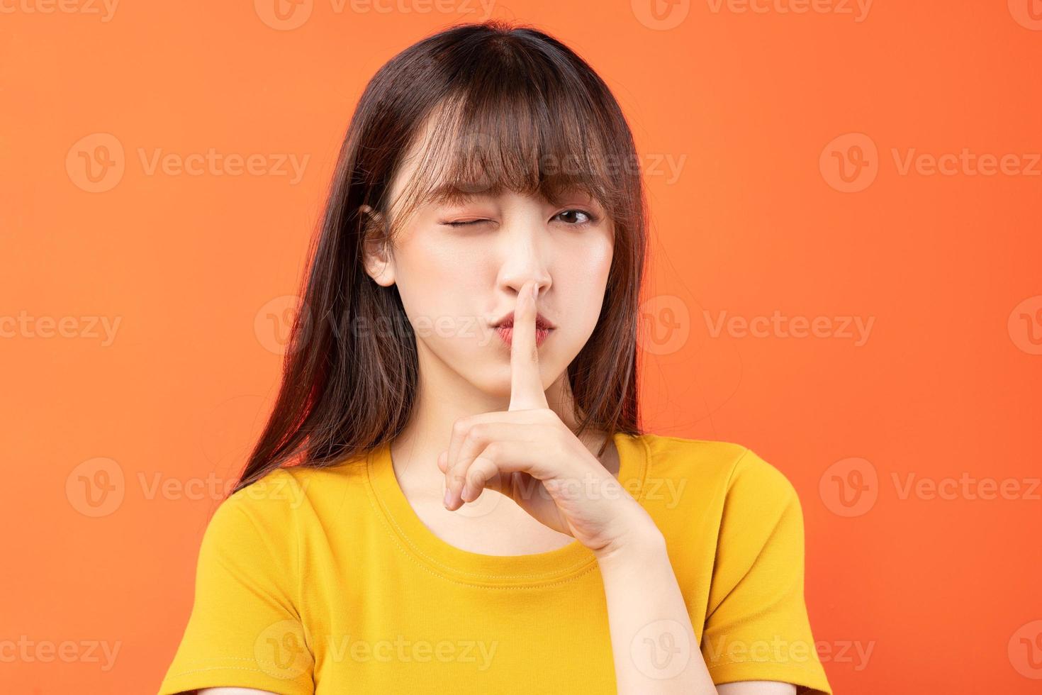 Imagen de la joven mujer asiática con camiseta amarilla sobre fondo naranja foto