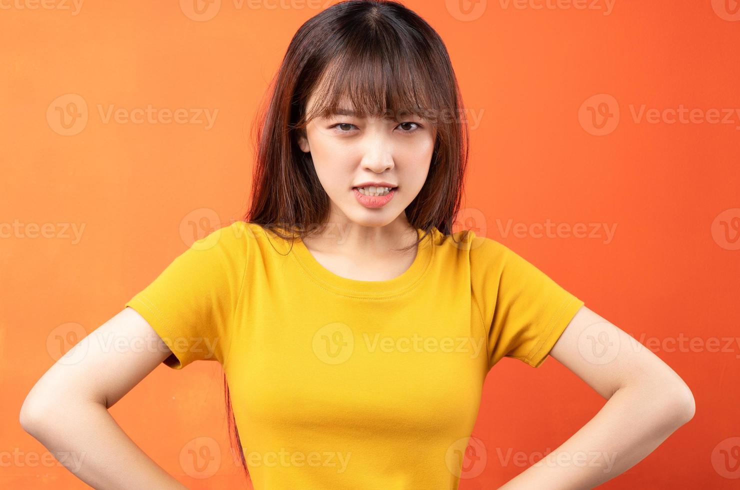 Imagen de la joven mujer asiática con camiseta amarilla sobre fondo naranja foto