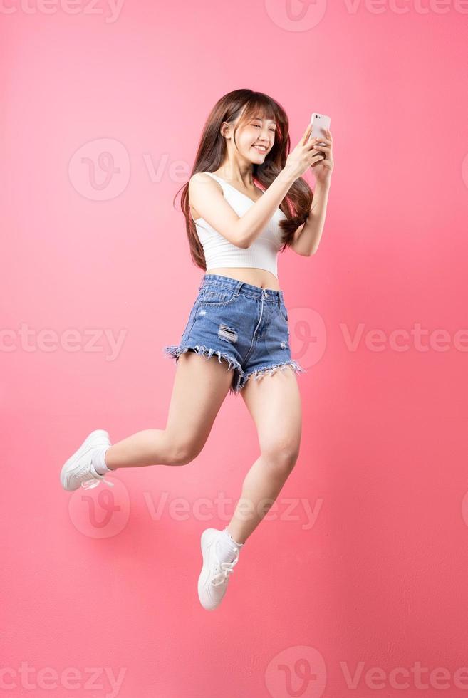 Image of young Asian girl jumping on pink background photo