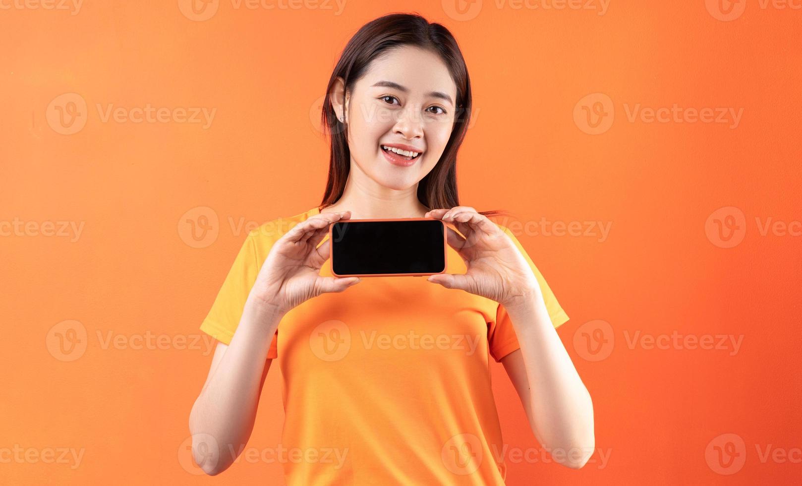 Young Asian woman holding smartphone with empty screen photo