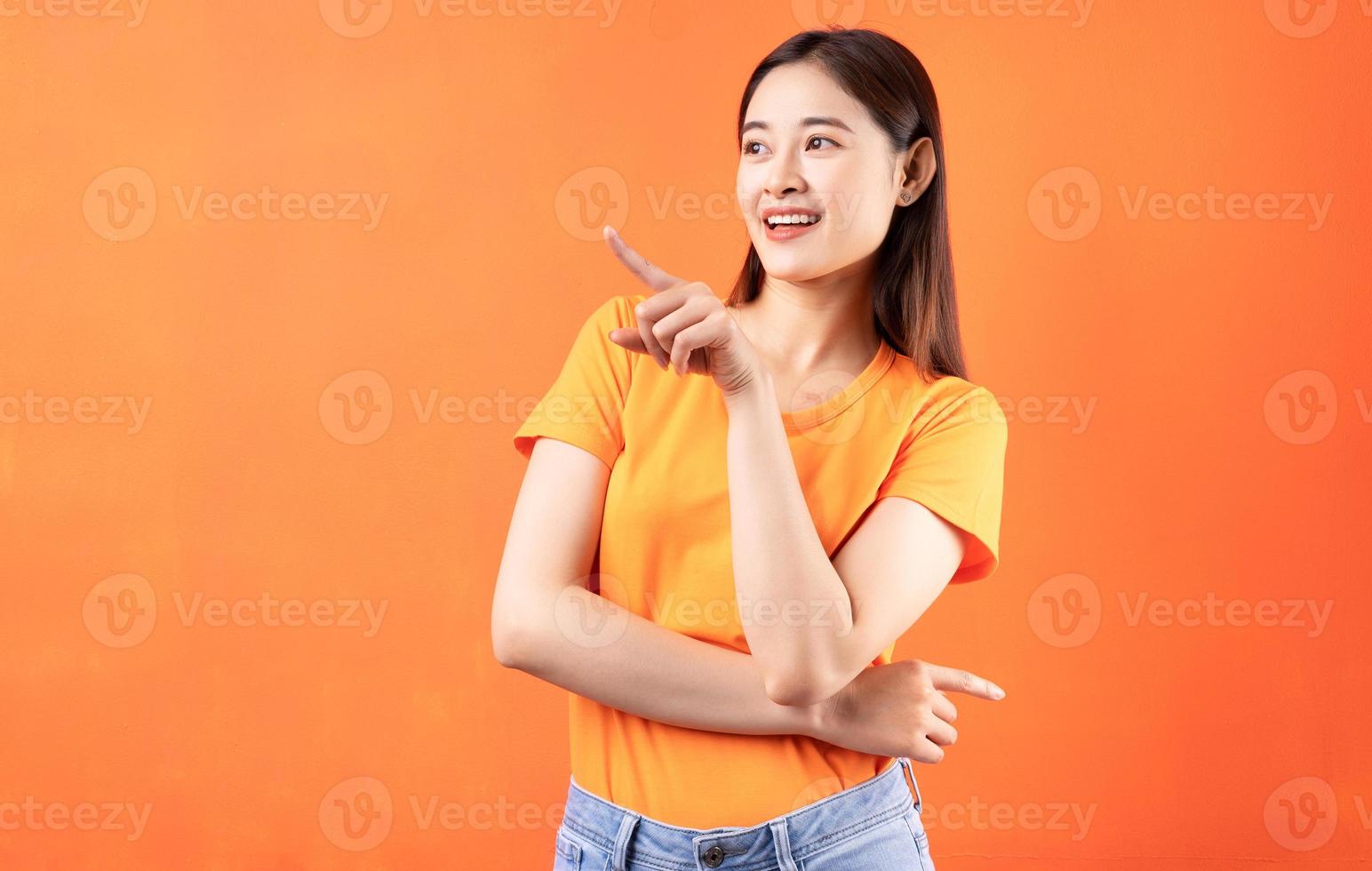 Image of young Asian woman wearing orange t-shirt on orange background photo