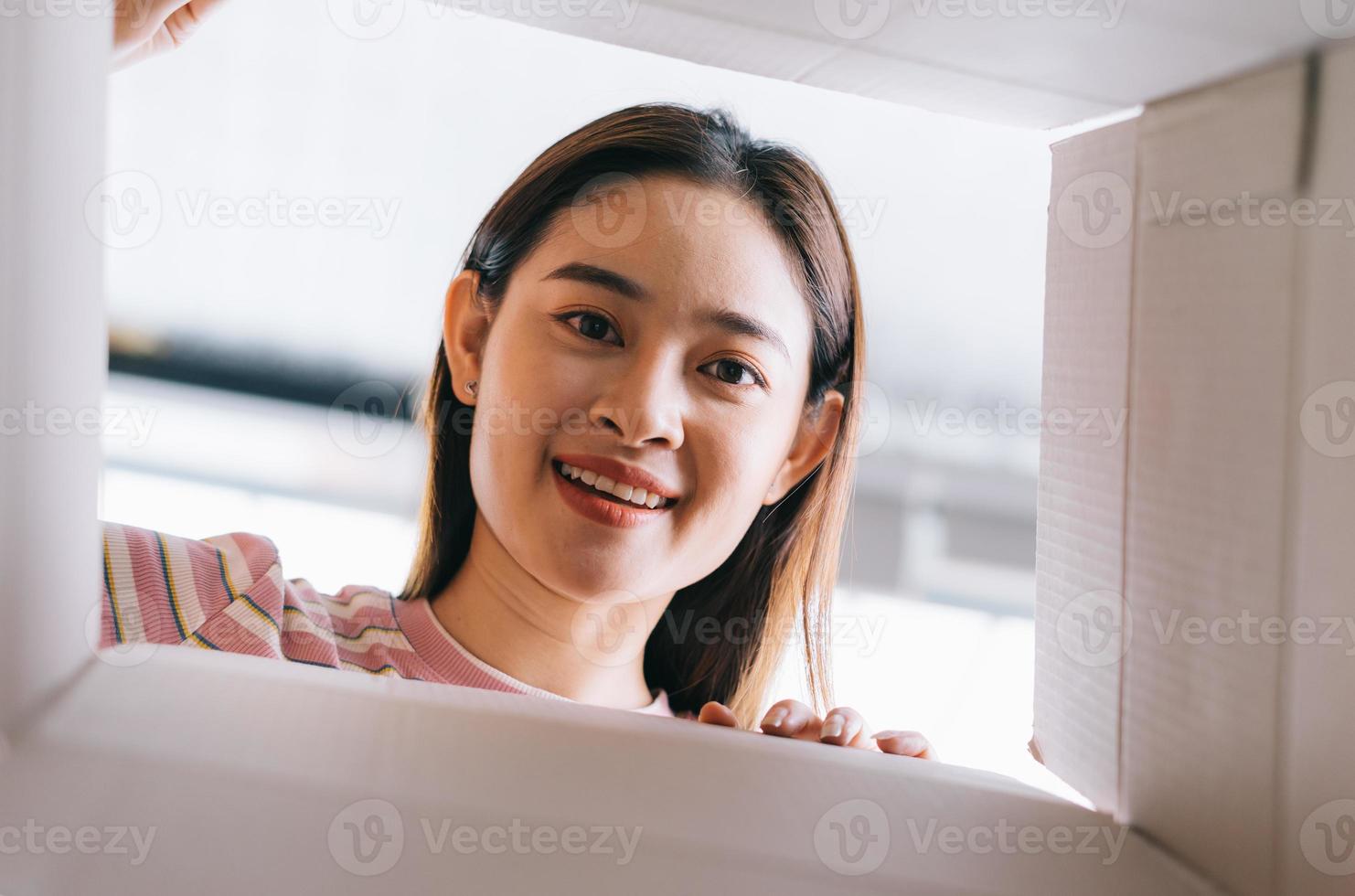 Young Asian woman opens the new package that has been sent home photo