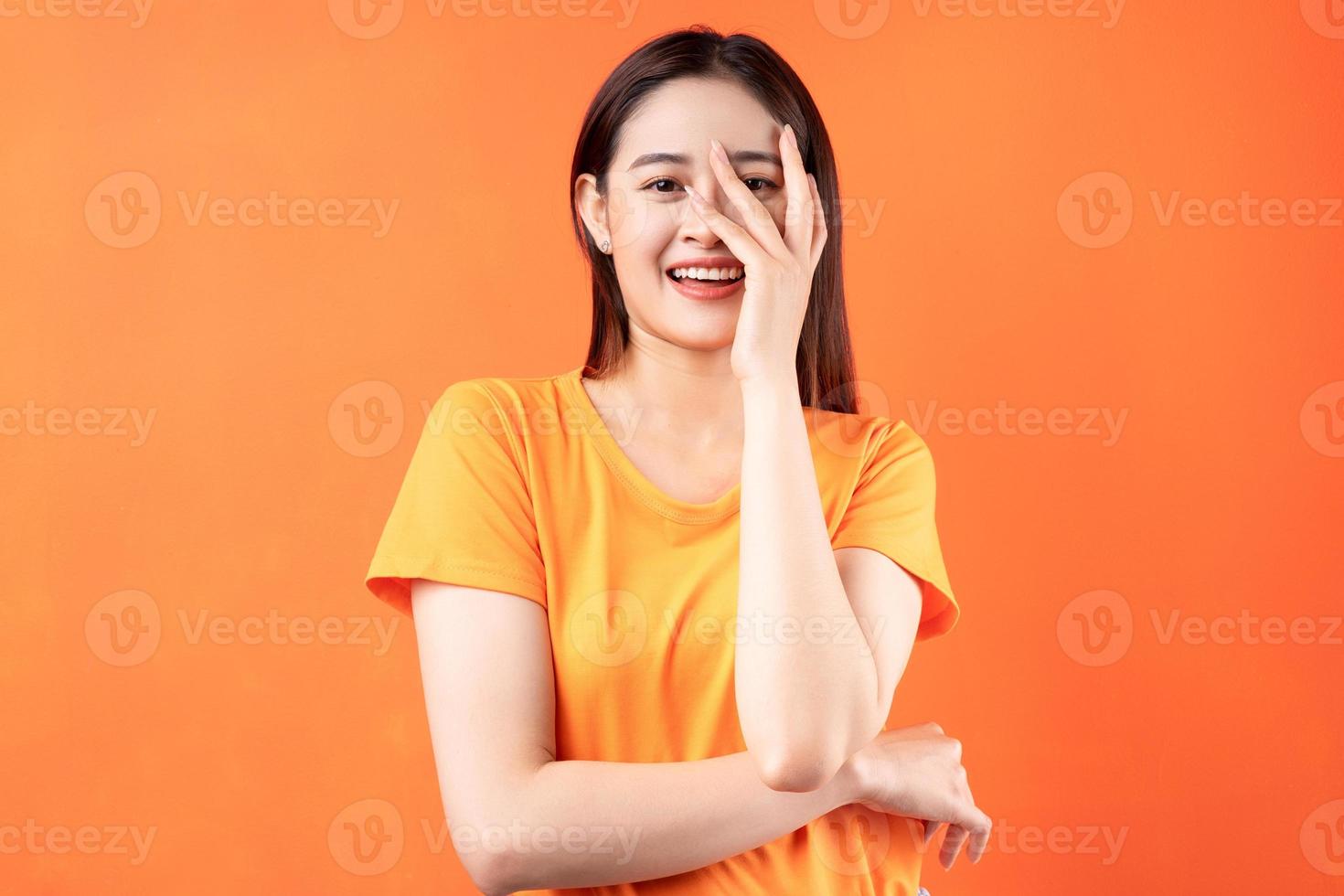 Image of young Asian woman wearing orange t-shirt on orange background photo