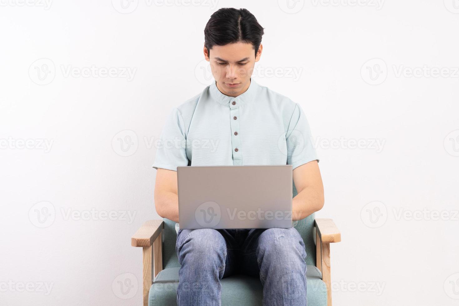 hombre guapo con laptop sentado en el sofá de trabajo foto