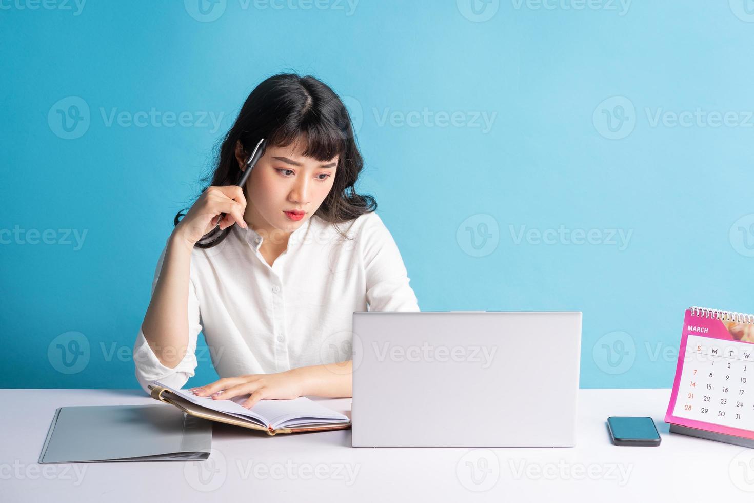 Joven mujer de negocios asiática trabajando sobre fondo azul. foto