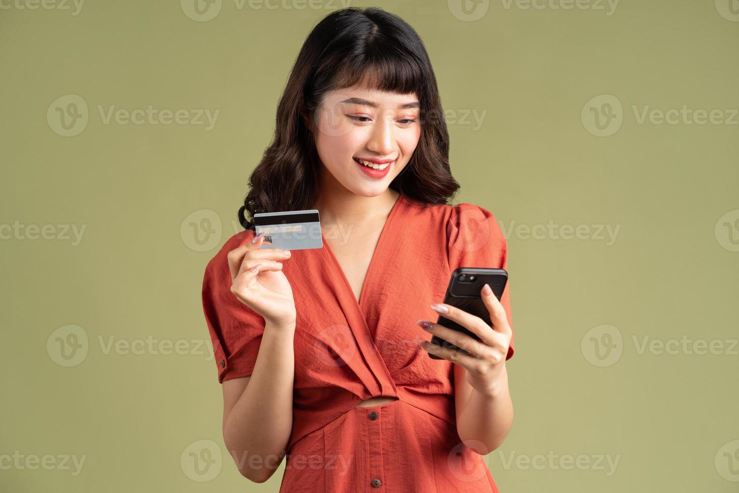 Asian woman holding a bank card and staring at her phone photo