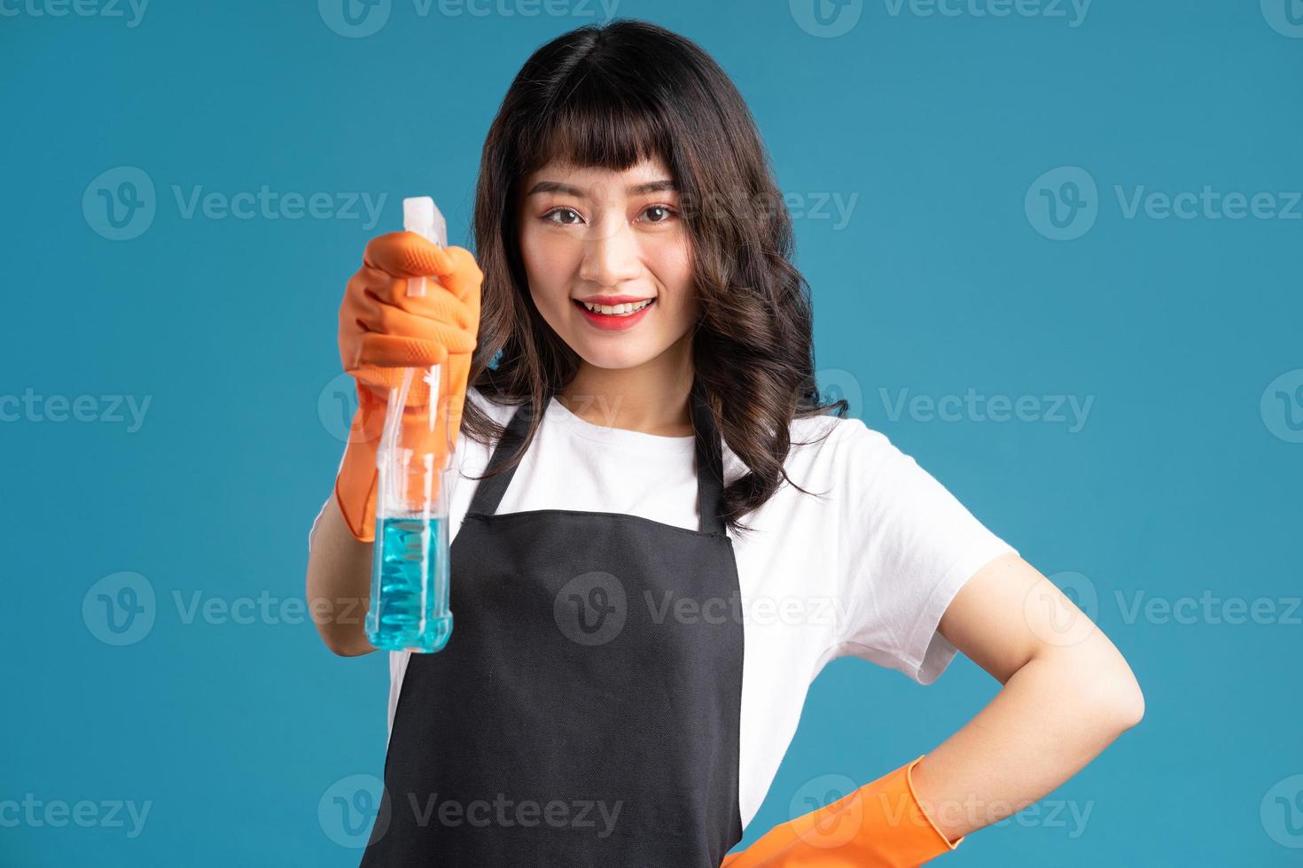 Una foto de una mujer asiática en un delantal y guantes preparándose para el trabajo de limpieza