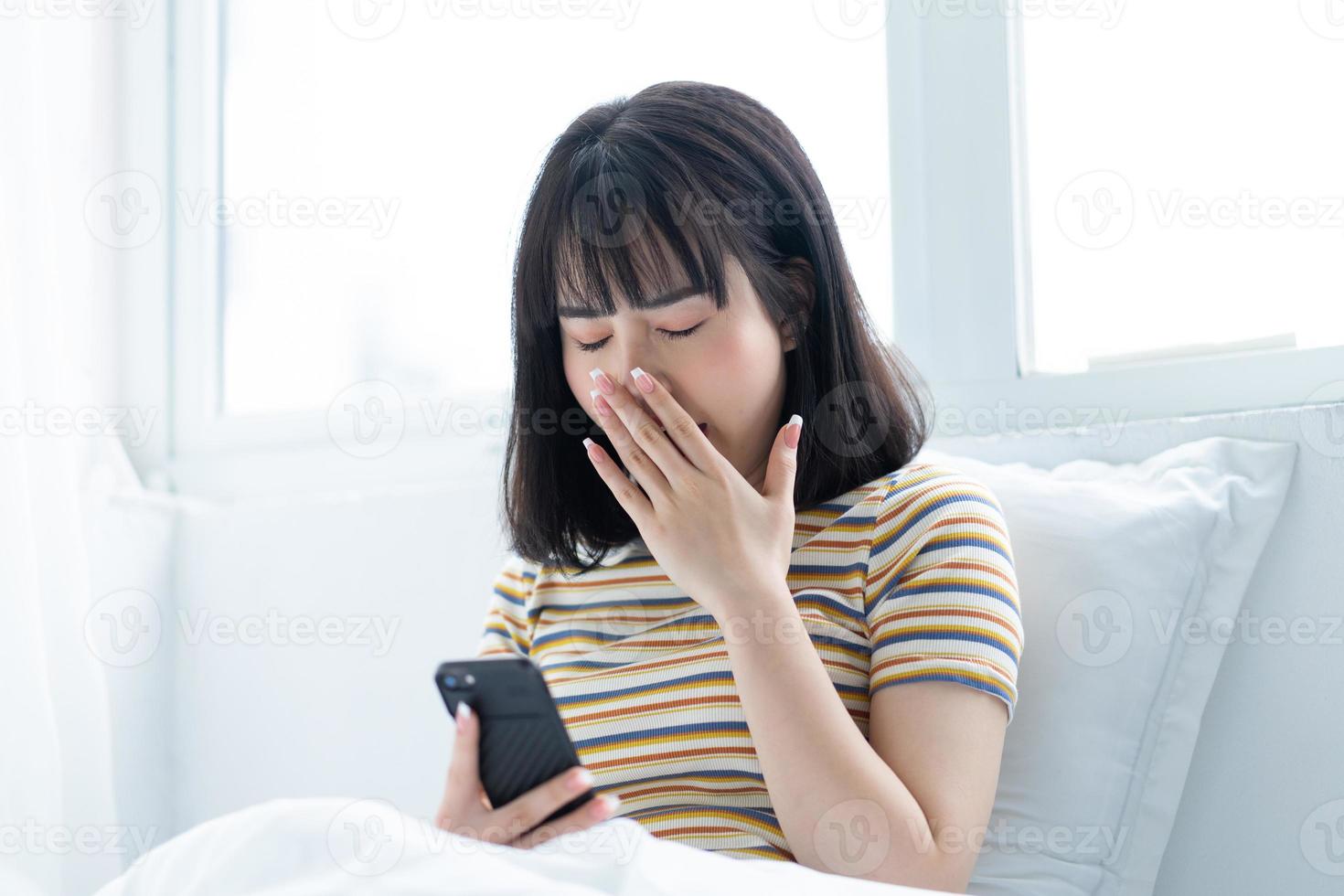 Beautiful Asian woman using phone on bed in bedroom photo