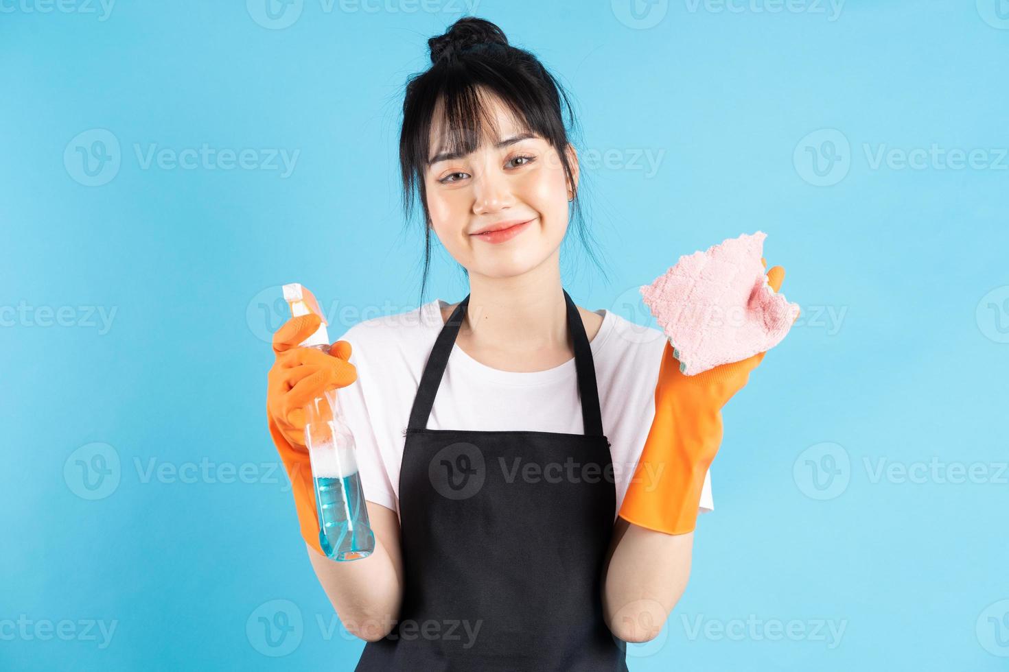 Ama de casa asiática lleva guantes naranjas y sostiene un chorro de agua en la mano foto