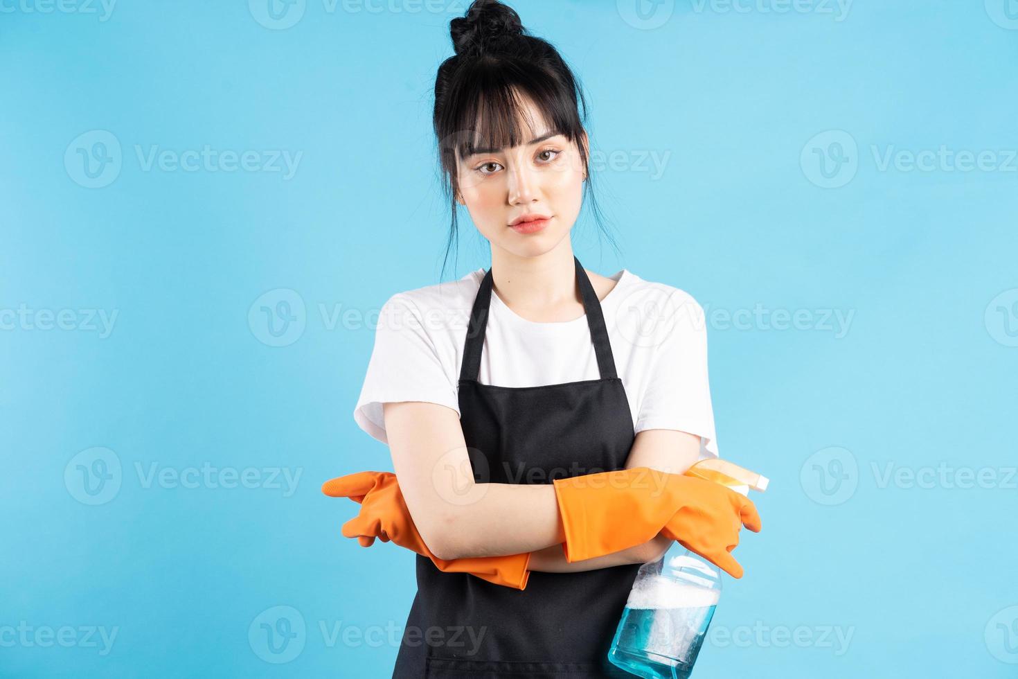 Asian housewife is wearing orange gloves and holding a spray of water in her hand photo
