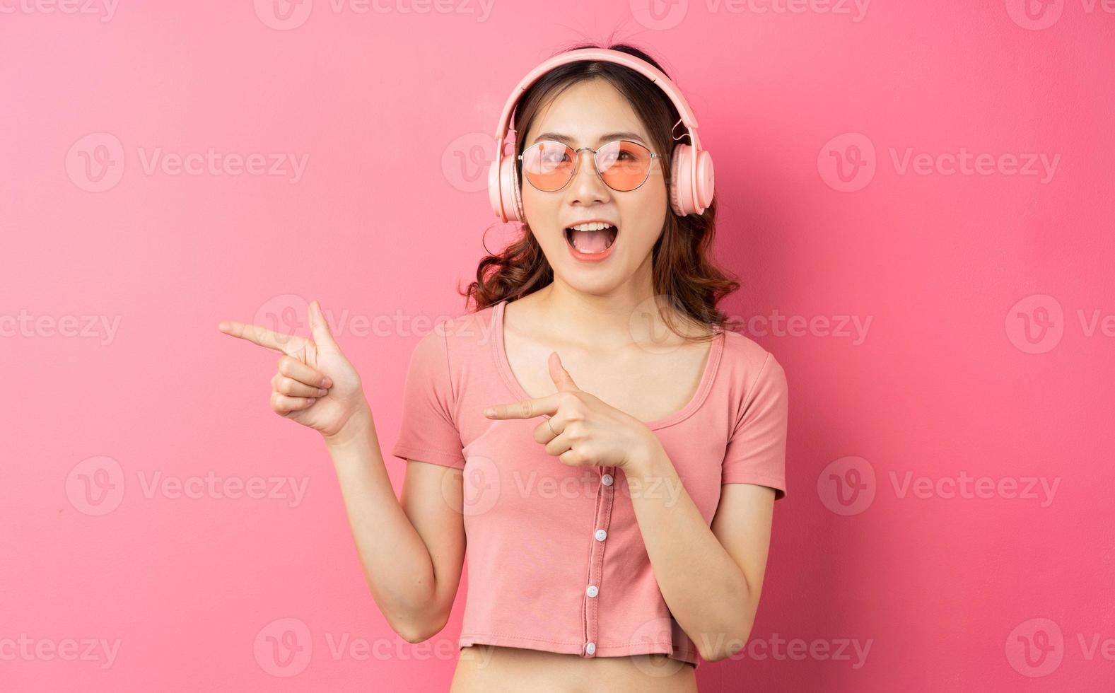 Beautiful young girl wearing pink headphones on a pink background photo