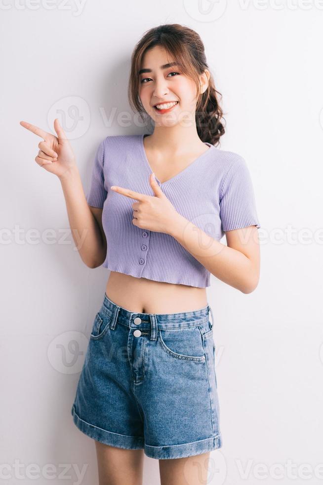 Cheerful young Asian girl pointing on white background photo