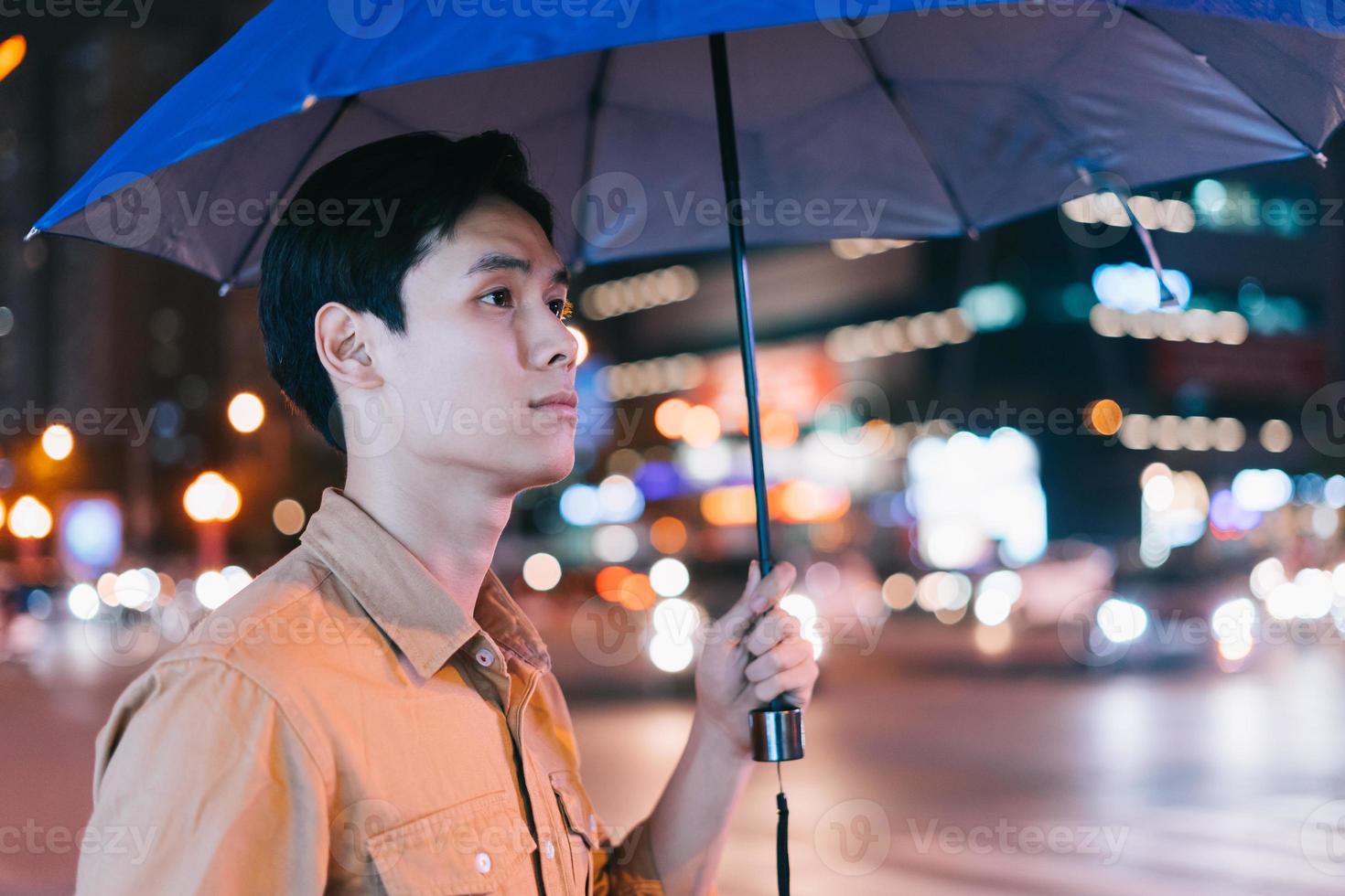 Hombre asiático está caminando por la calle por la noche sintiéndose perdido foto