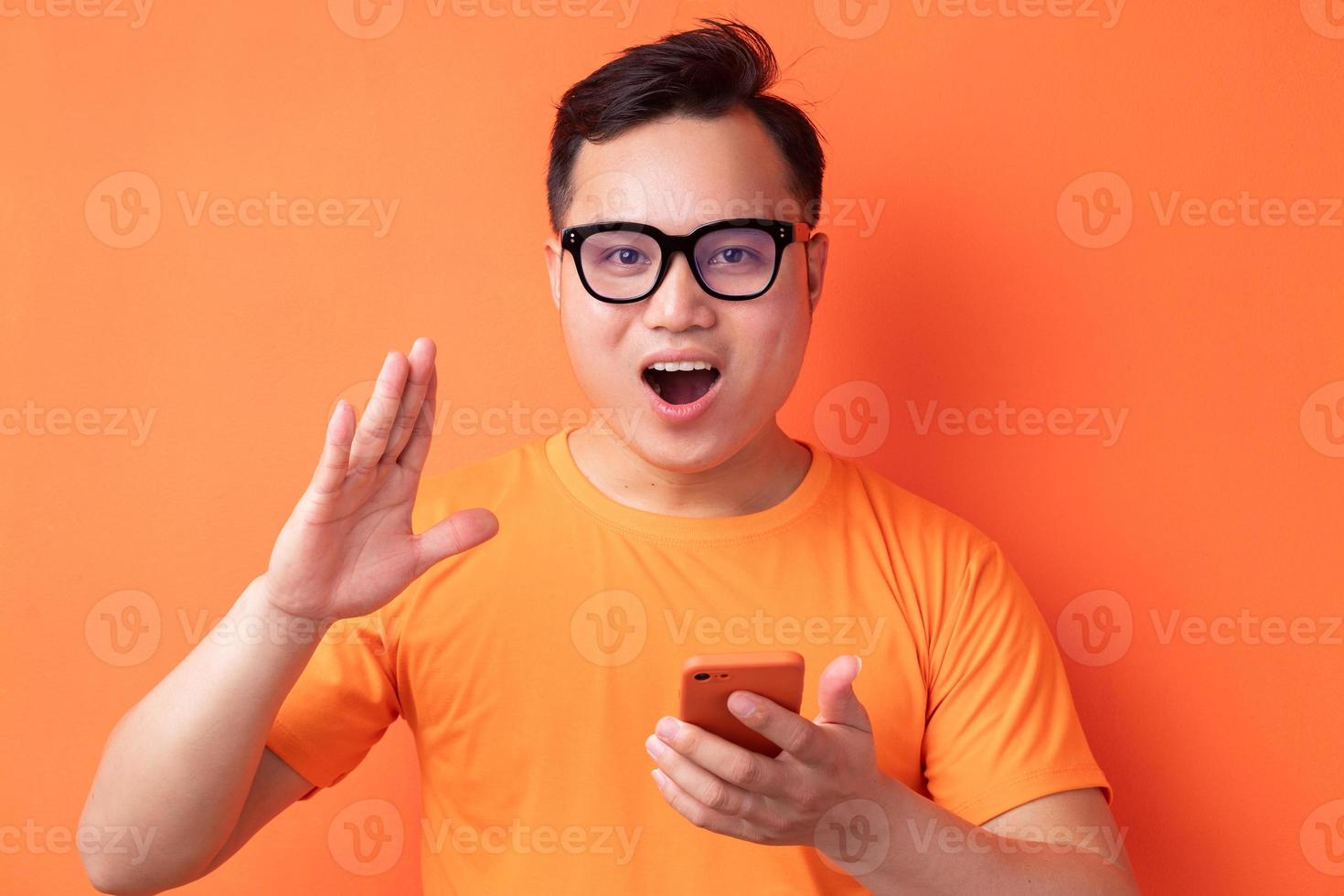 joven asiático sosteniendo el teléfono con una expresión de sorpresa foto