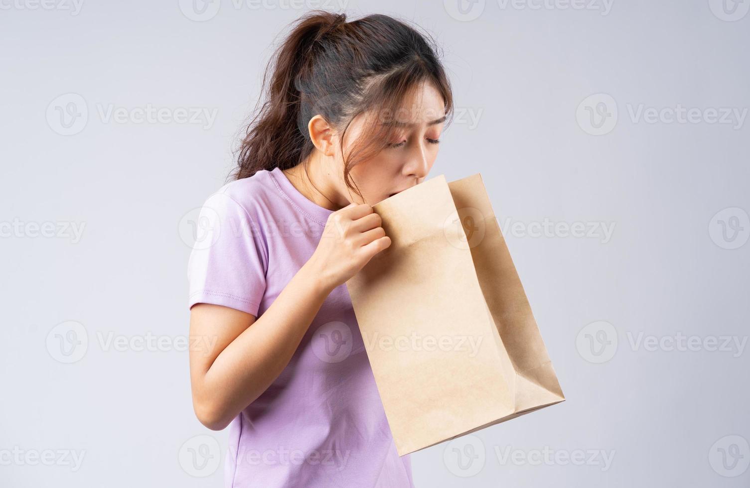 Young Asian girl is gagging in a paper bag photo