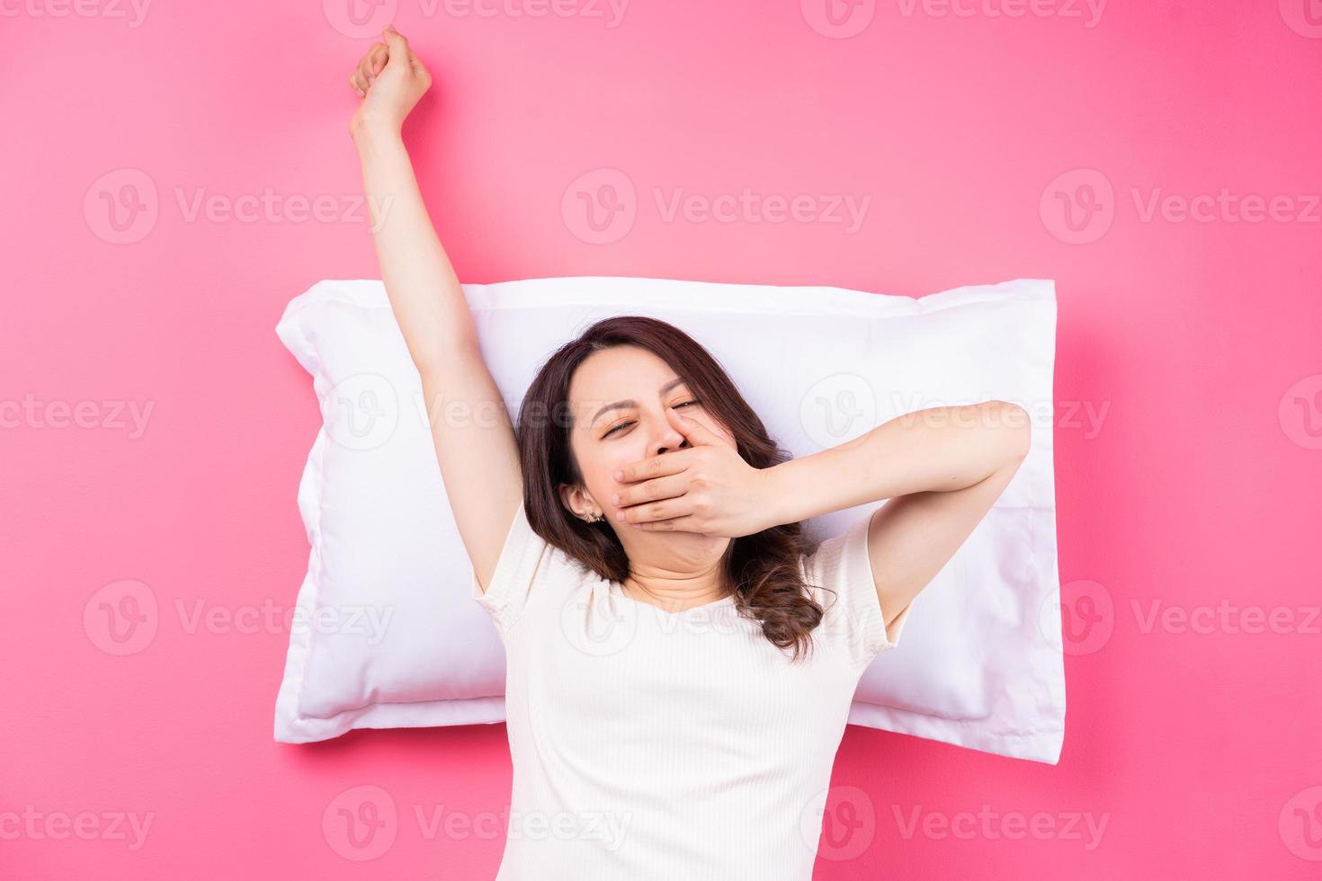 mujer asiática durmiendo sobre fondo rosa foto