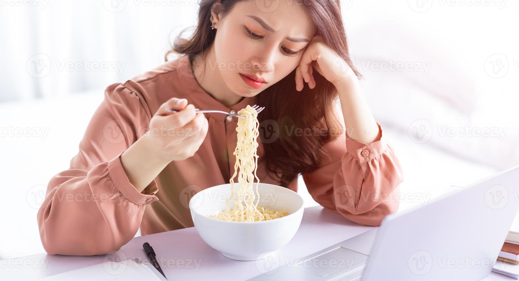 empresaria asiática tiene que comer fideos mientras trabaja foto