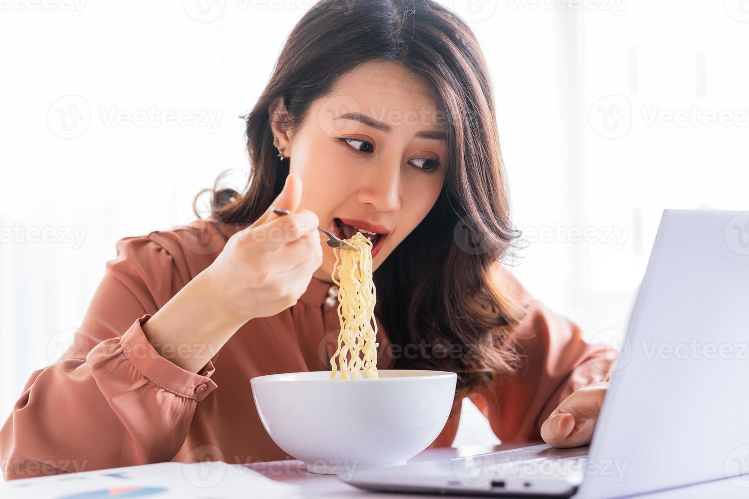 empresaria asiática tiene que comer fideos mientras trabaja foto