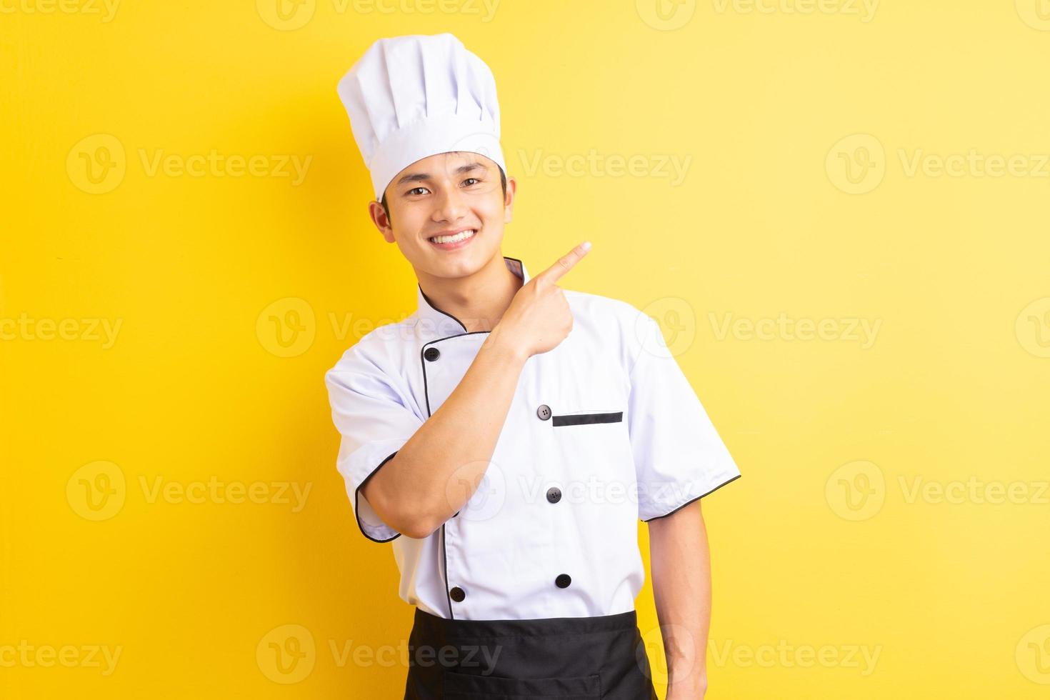 Image of Asian male chef on yellow background photo