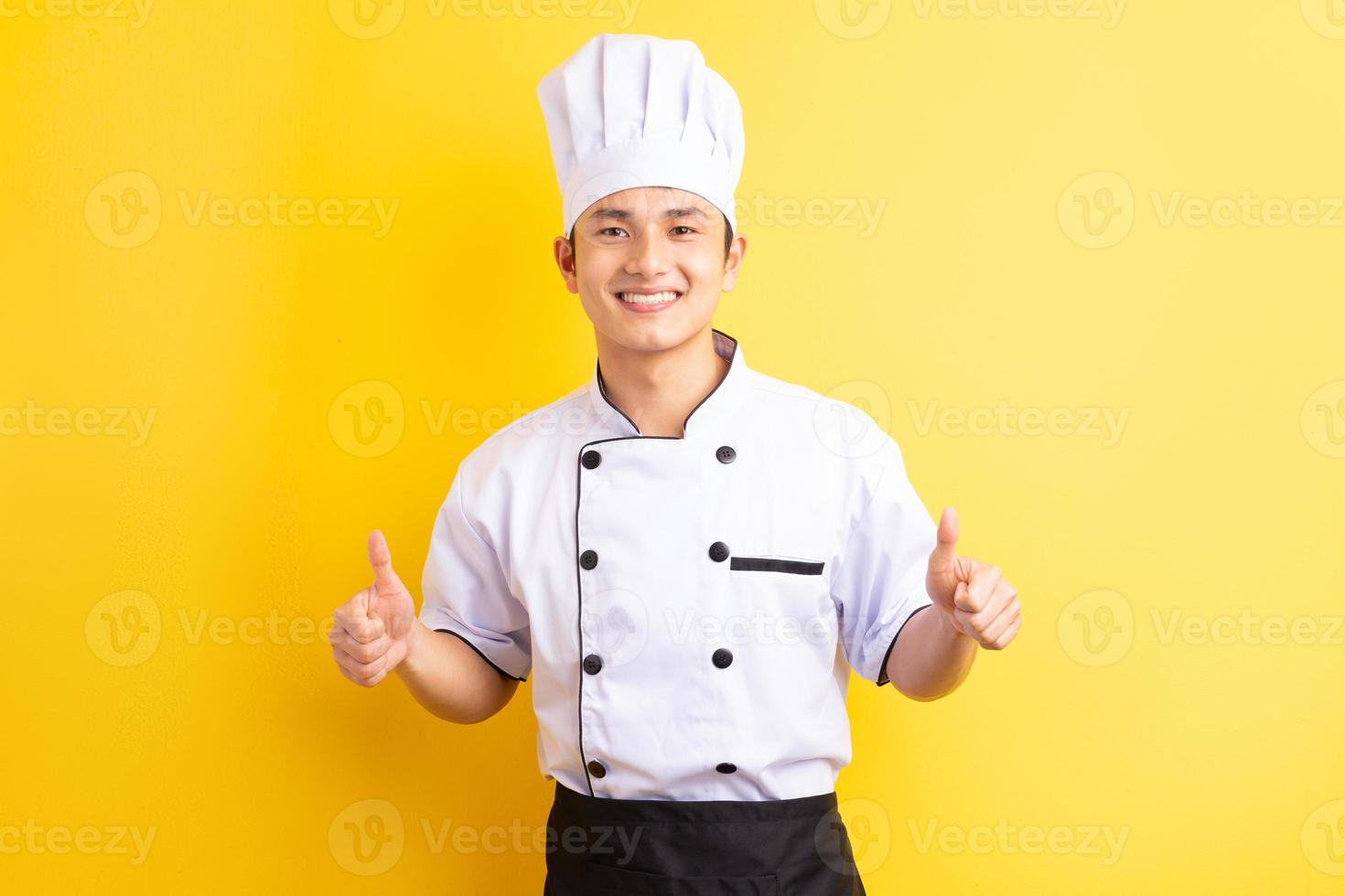 Image of Asian male chef on yellow background photo