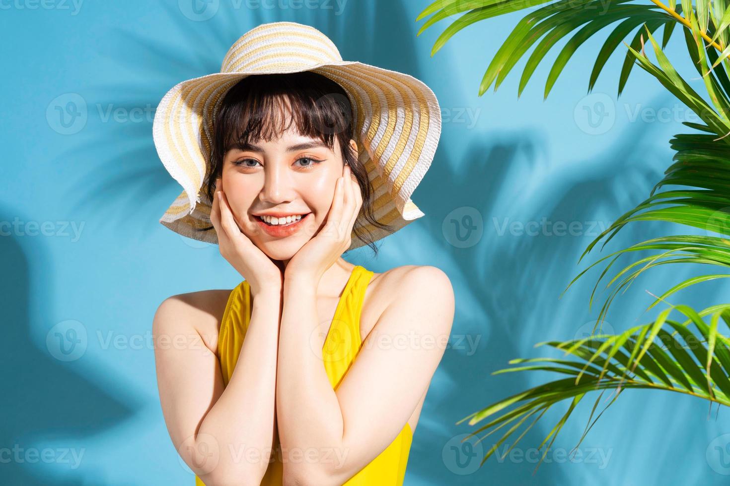 Beautiful Asian woman wearing yellow jumpsuit on blue background and, summer concept photo