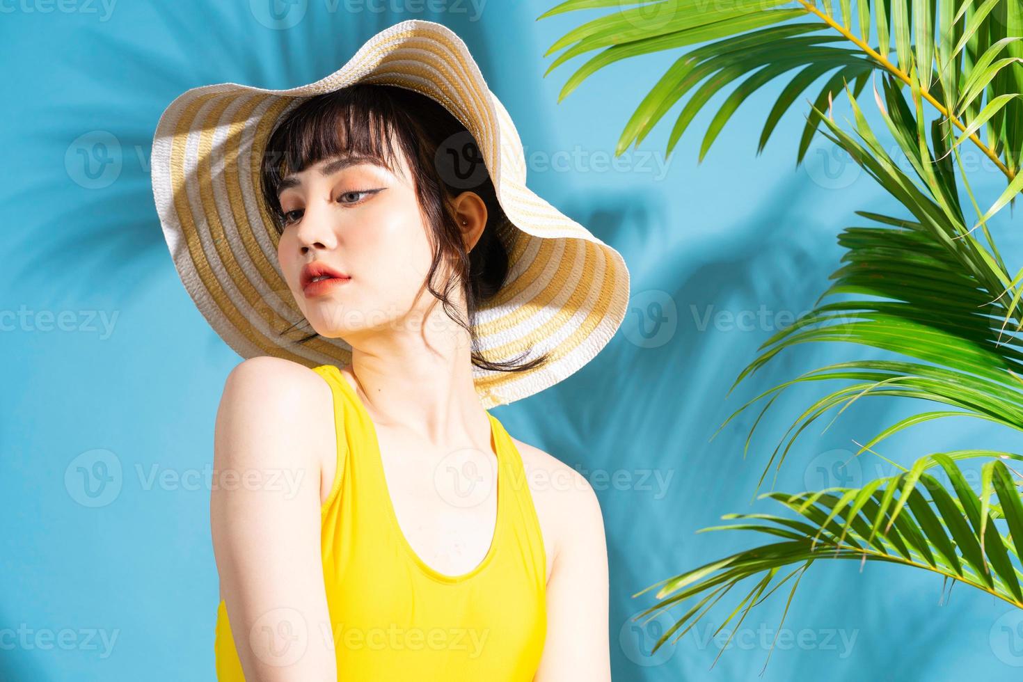 Hermosa mujer asiática vistiendo mono amarillo sobre fondo azul y concepto de verano foto