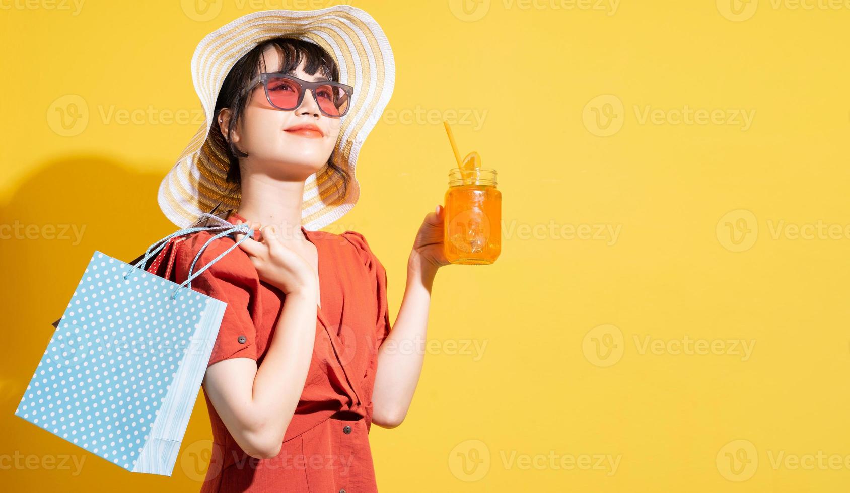 Joven empresaria asiática sosteniendo bolsas de la compra posando sobre fondo amarillo foto