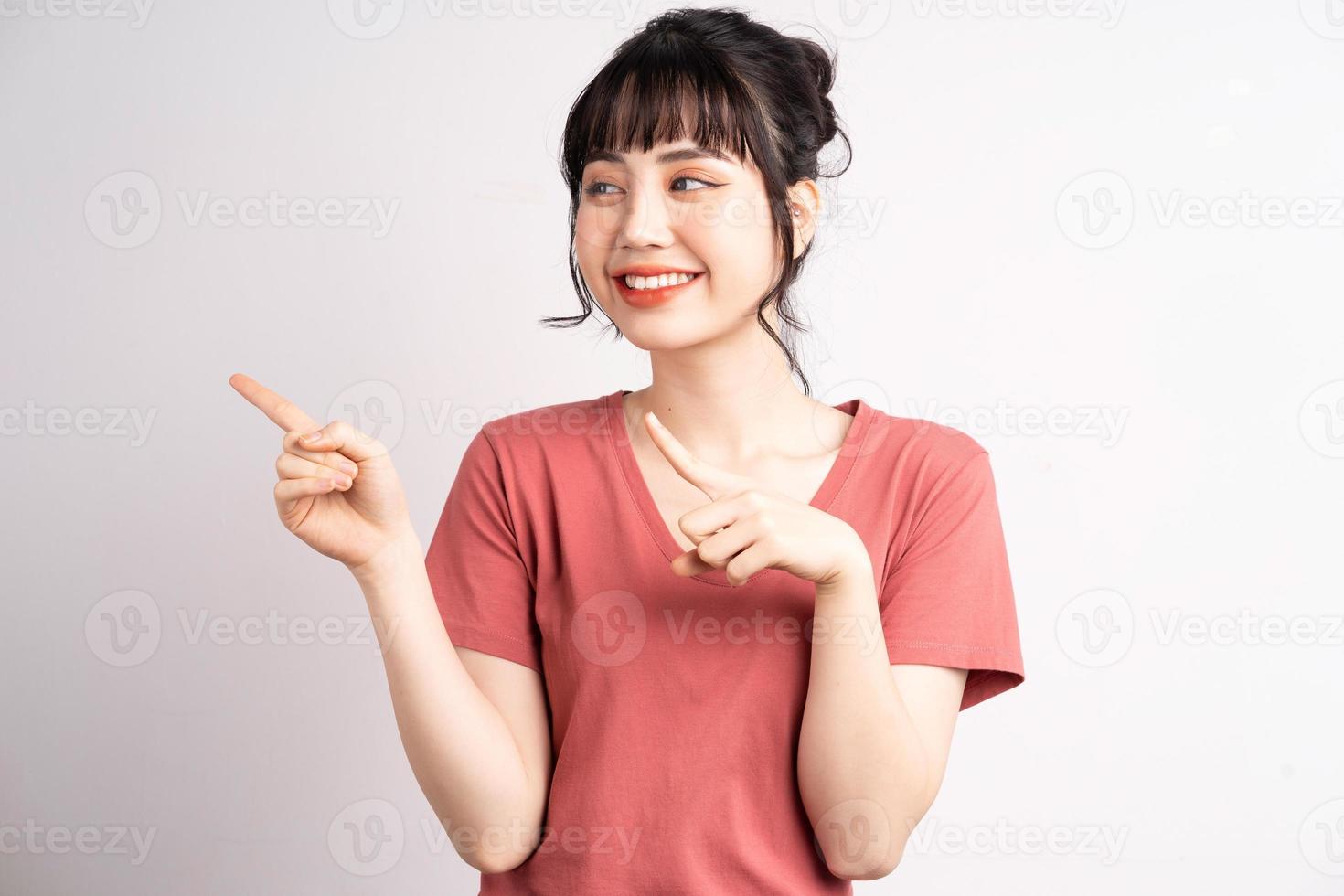 Joven mujer asiática posando sobre fondo blanco, usando el dedo para señalar y mostrar, gesto con la mano foto