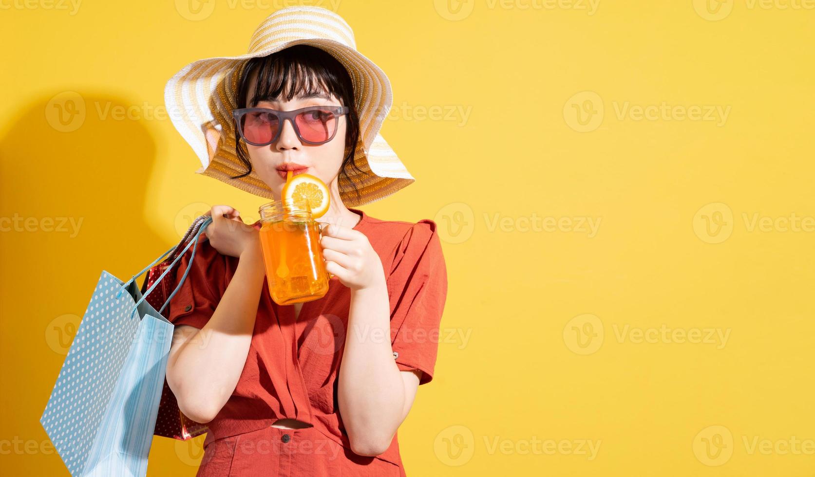 Young Asian businesswoman holding shopping bags posing on yellow background photo