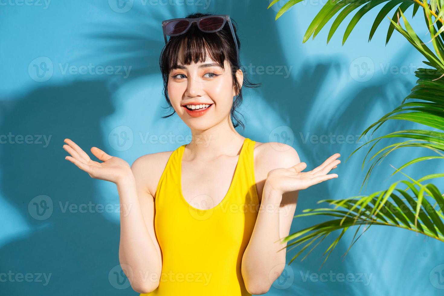 Beautiful Asian woman wearing yellow jumpsuit on blue background and, summer concept photo