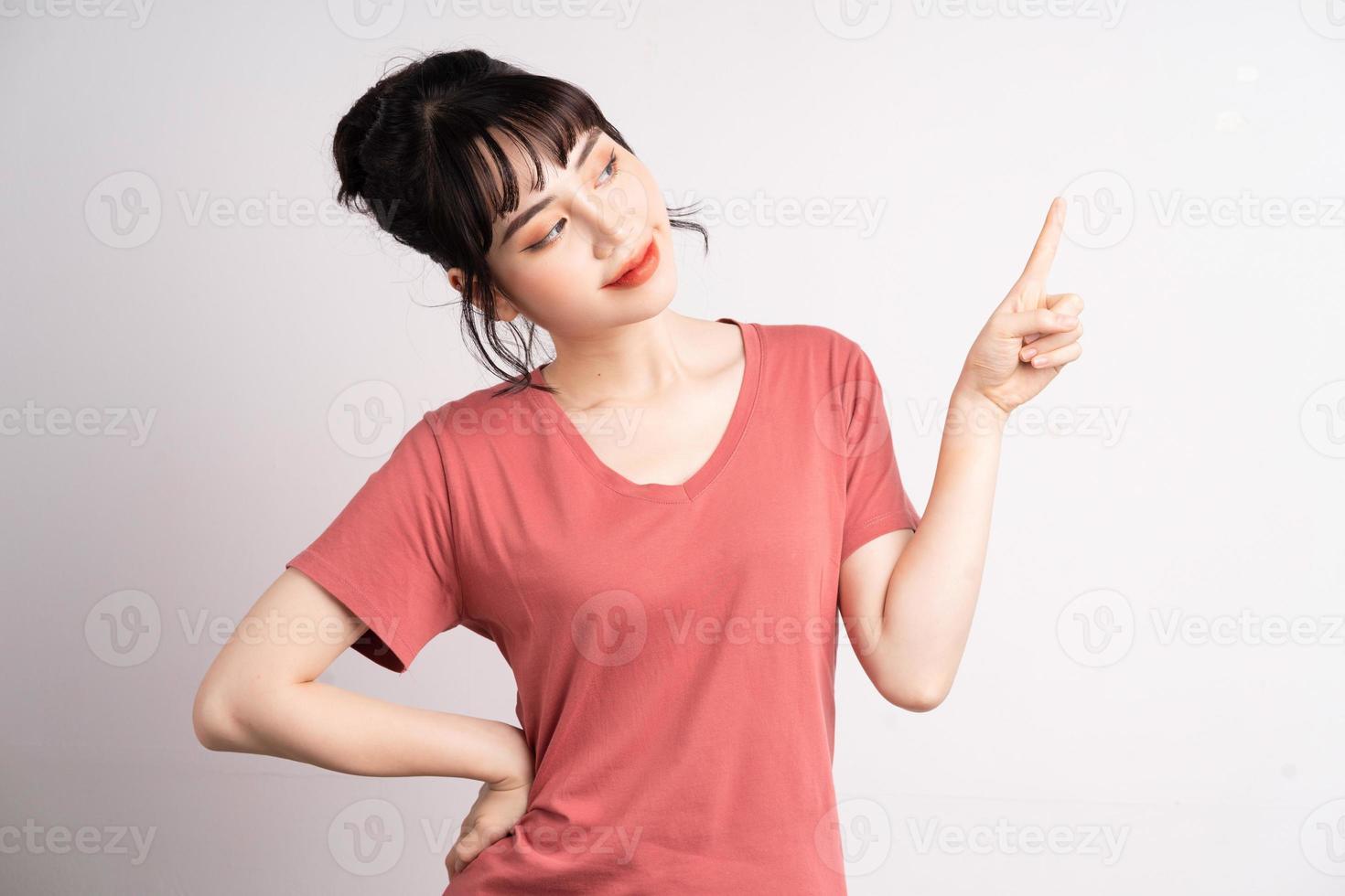 Joven mujer asiática posando sobre fondo blanco, usando el dedo para señalar y mostrar, gesto con la mano foto