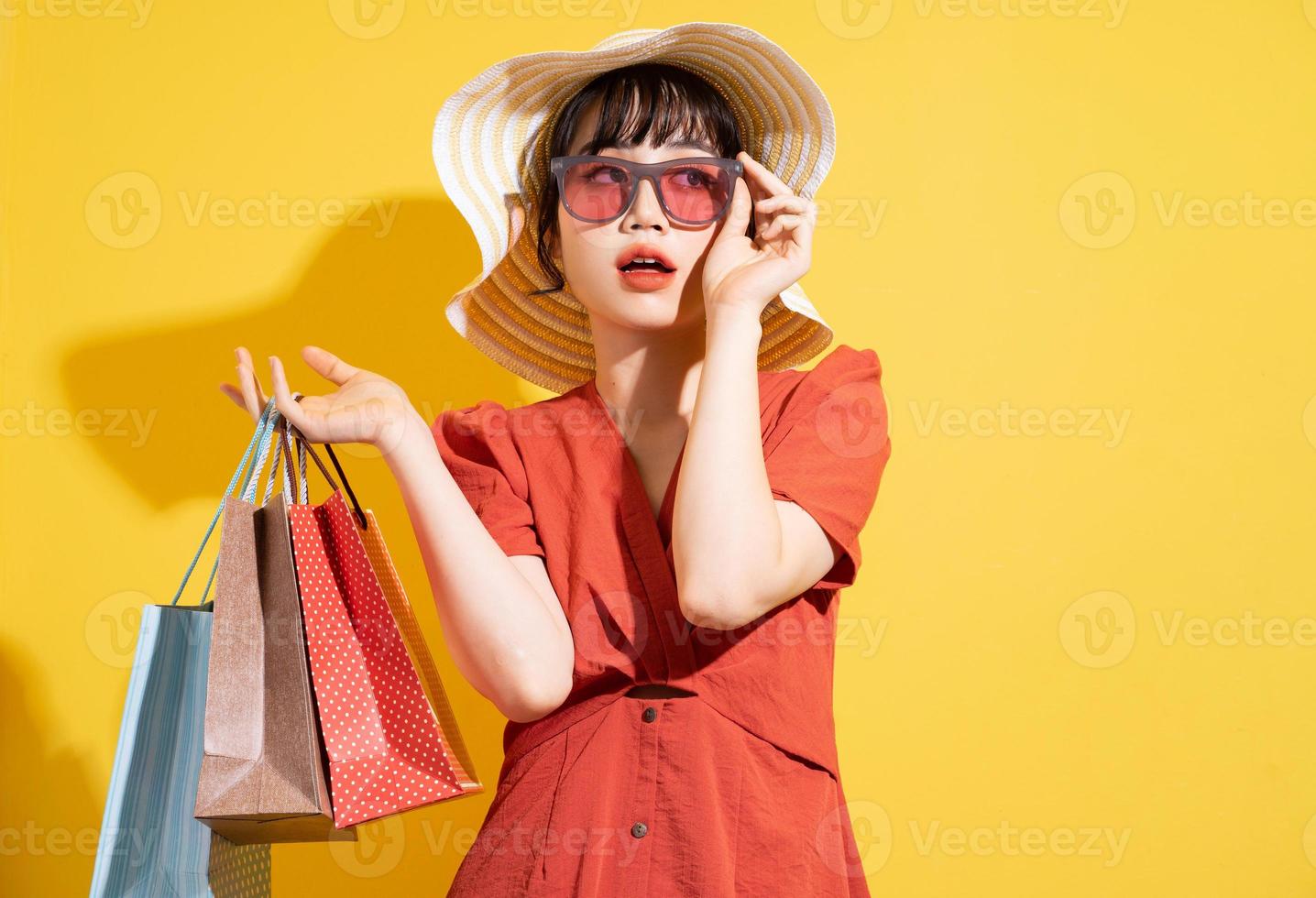 Joven empresaria asiática sosteniendo bolsas de la compra posando sobre fondo amarillo foto