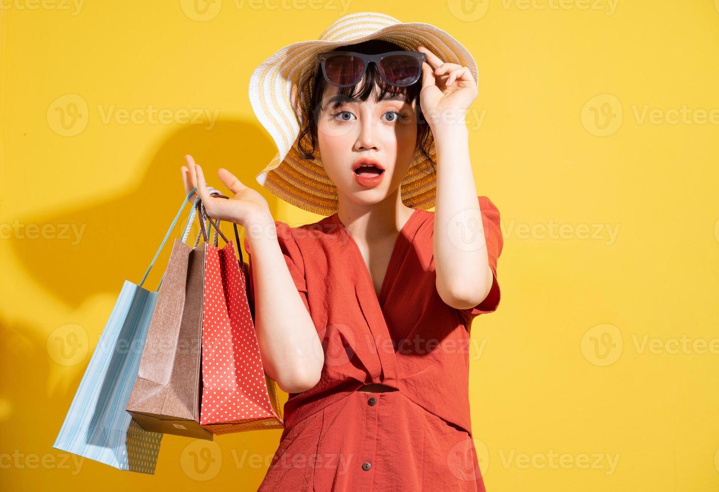 Young Asian businesswoman holding shopping bags posing on yellow background photo