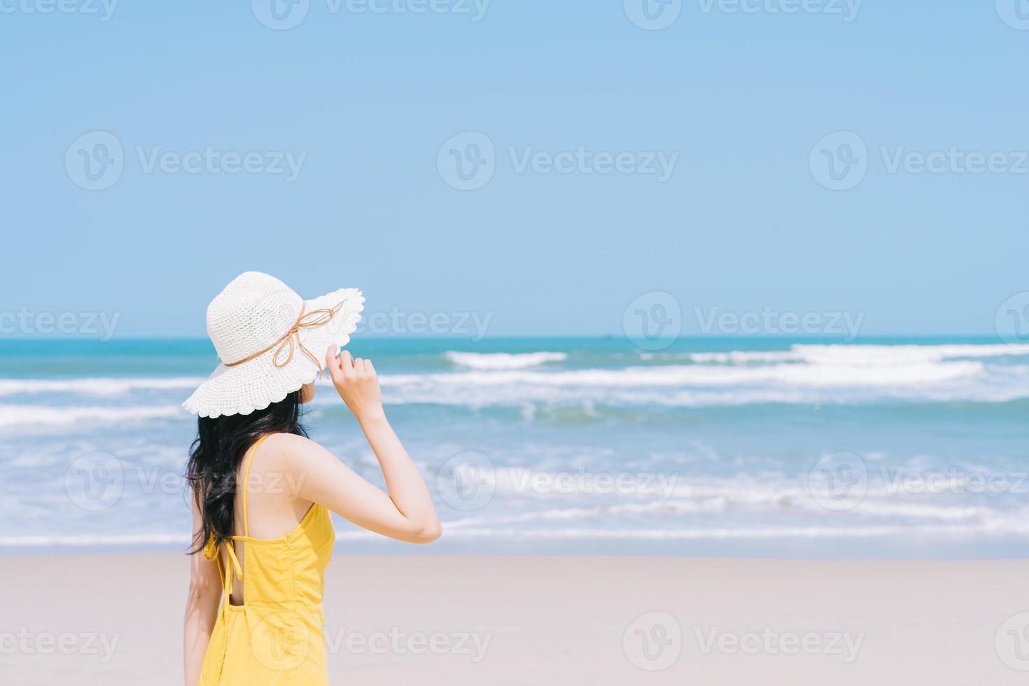 Joven mujer asiática disfrutando de las vacaciones de verano en la playa. foto