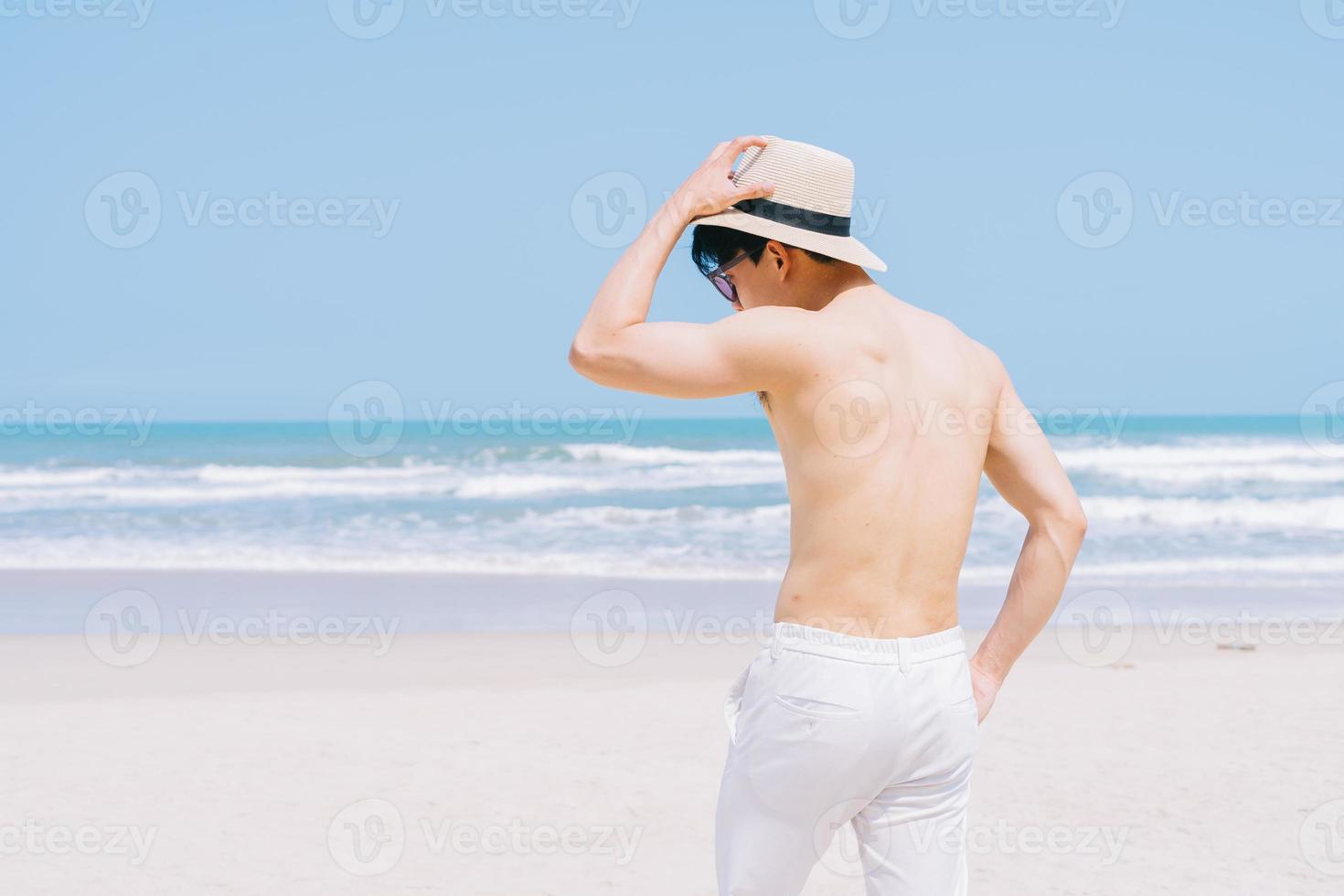 Young Asian man walking on the beach photo